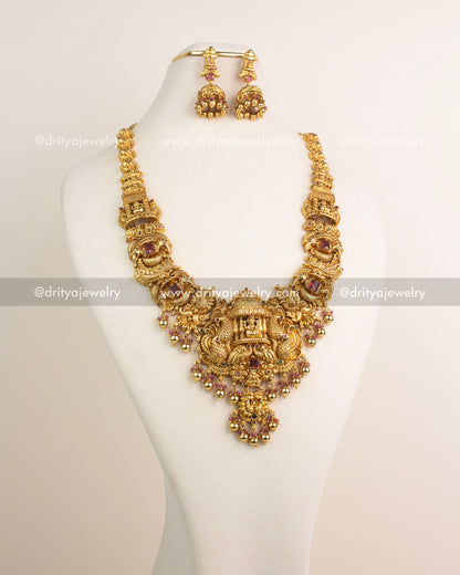 Ruby red stone temple long necklace with antique gold finish and intricate Nakshi carvings.