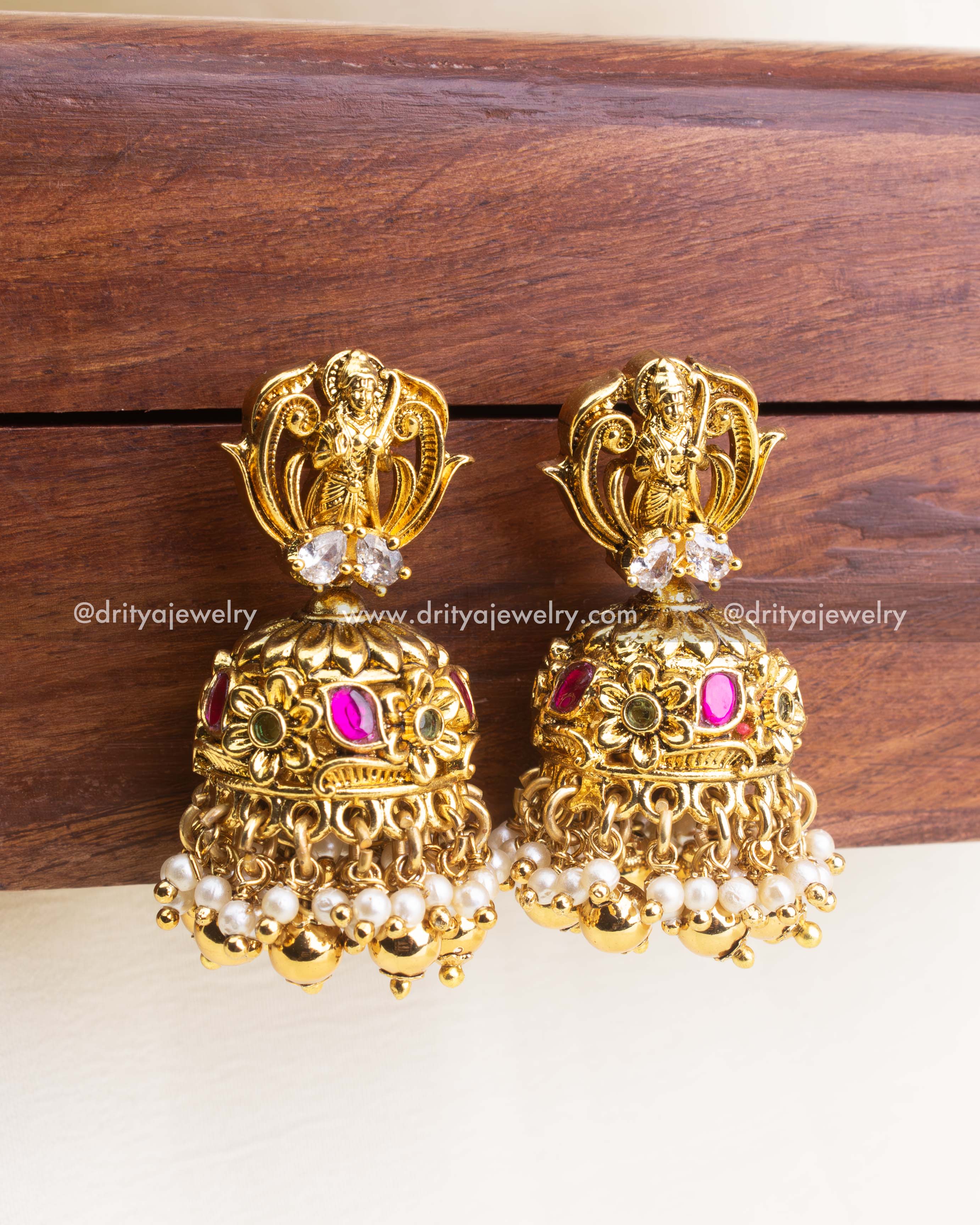 Traditional antique jhumka earrings with kemp stones, floral motifs, and pearl-gold hangings.