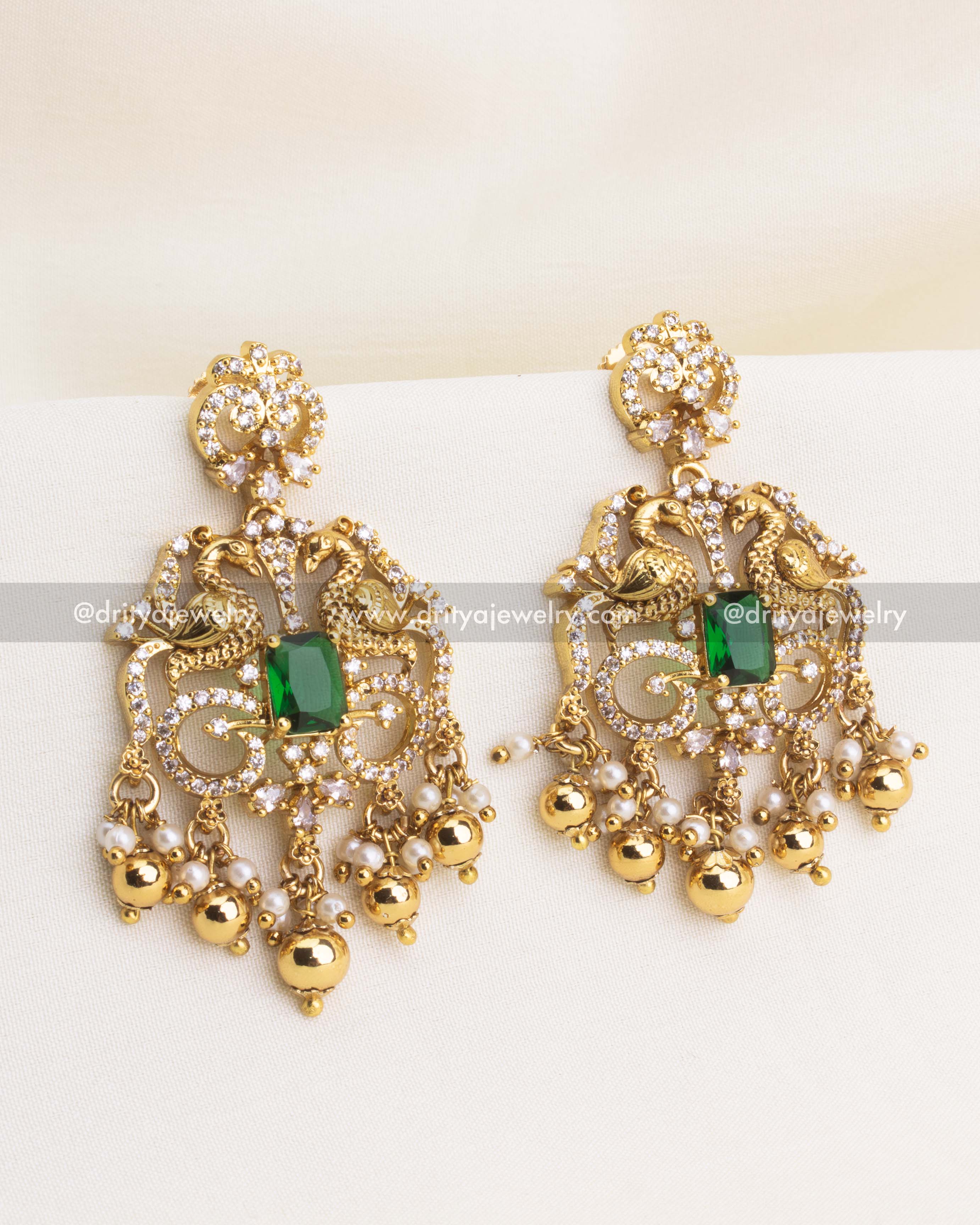 Antique earrings with peacock motifs, green rectangular CZ stones, and pearl-gold drops.