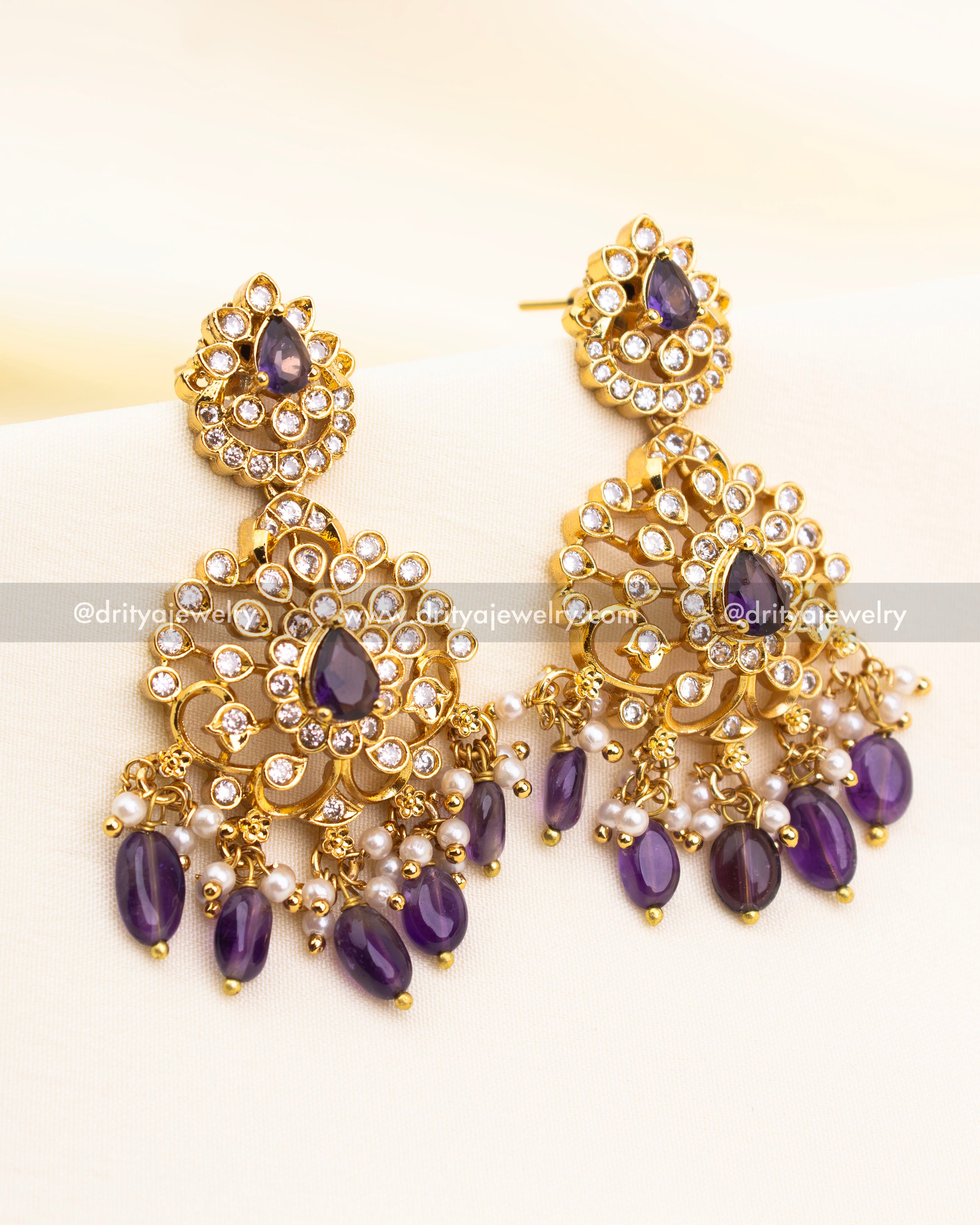 Three-layered floral earrings featuring CZ stones, purple drops, and faux pearl hangings.