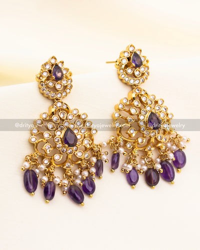 Three-layered floral earrings featuring CZ stones, purple drops, and faux pearl hangings.