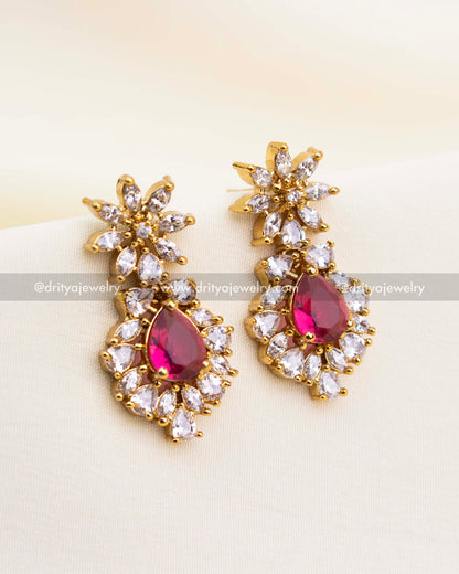 Gold earrings featuring red stones and CZ detailing in floral pattern.