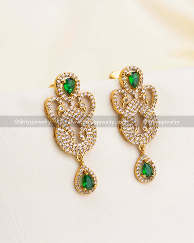 Elegant drop earrings with emerald green stones and gold-plated CZ-studded swirl design.