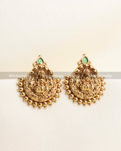 lose-up of antique gold Lakshmi pendant with bead clusters and green stone accent.