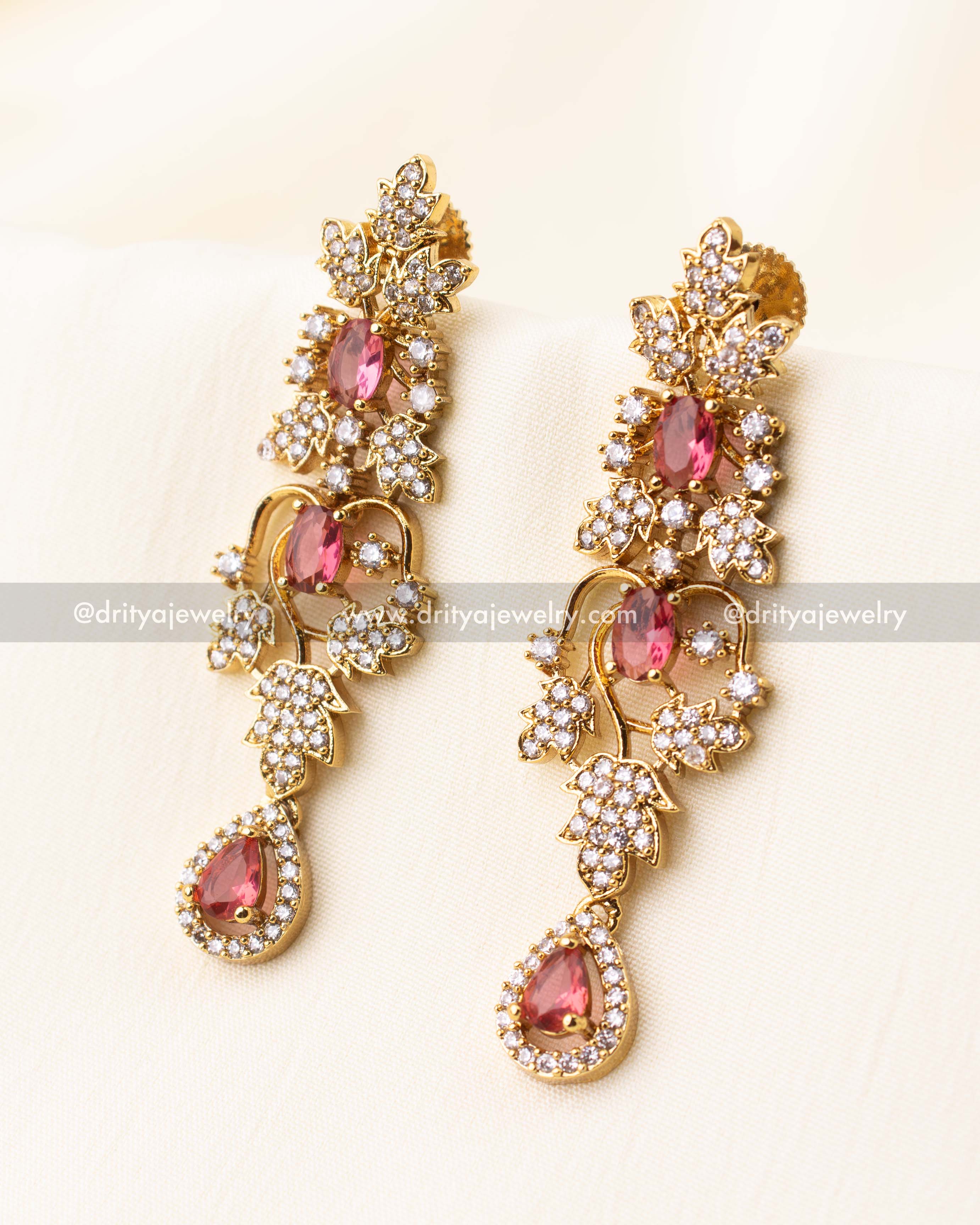 Gold-toned dangle earrings with ruby CZ stones and intricate floral detailing.