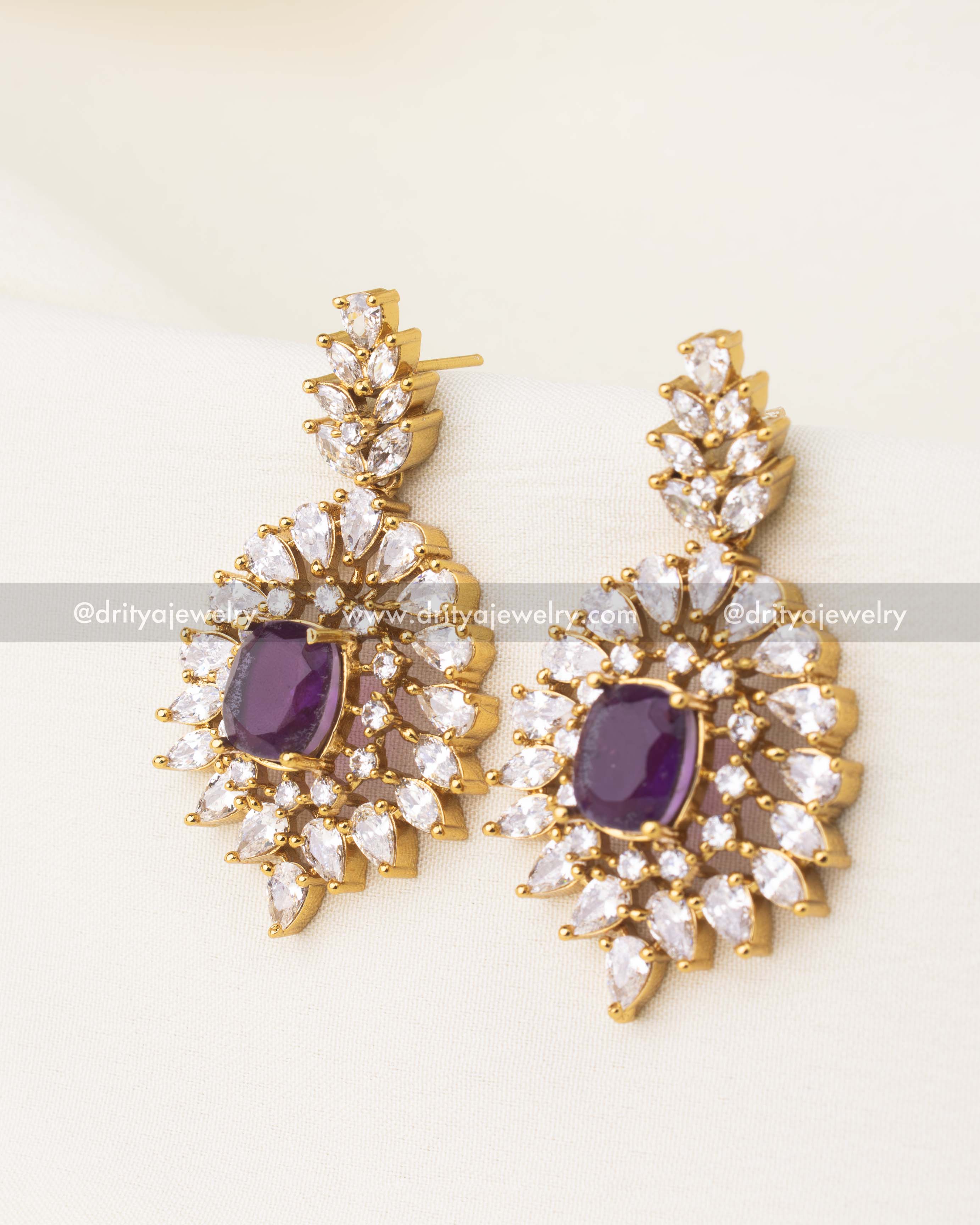 Statement earrings featuring royal‑purple center with layered CZ starburst halo.