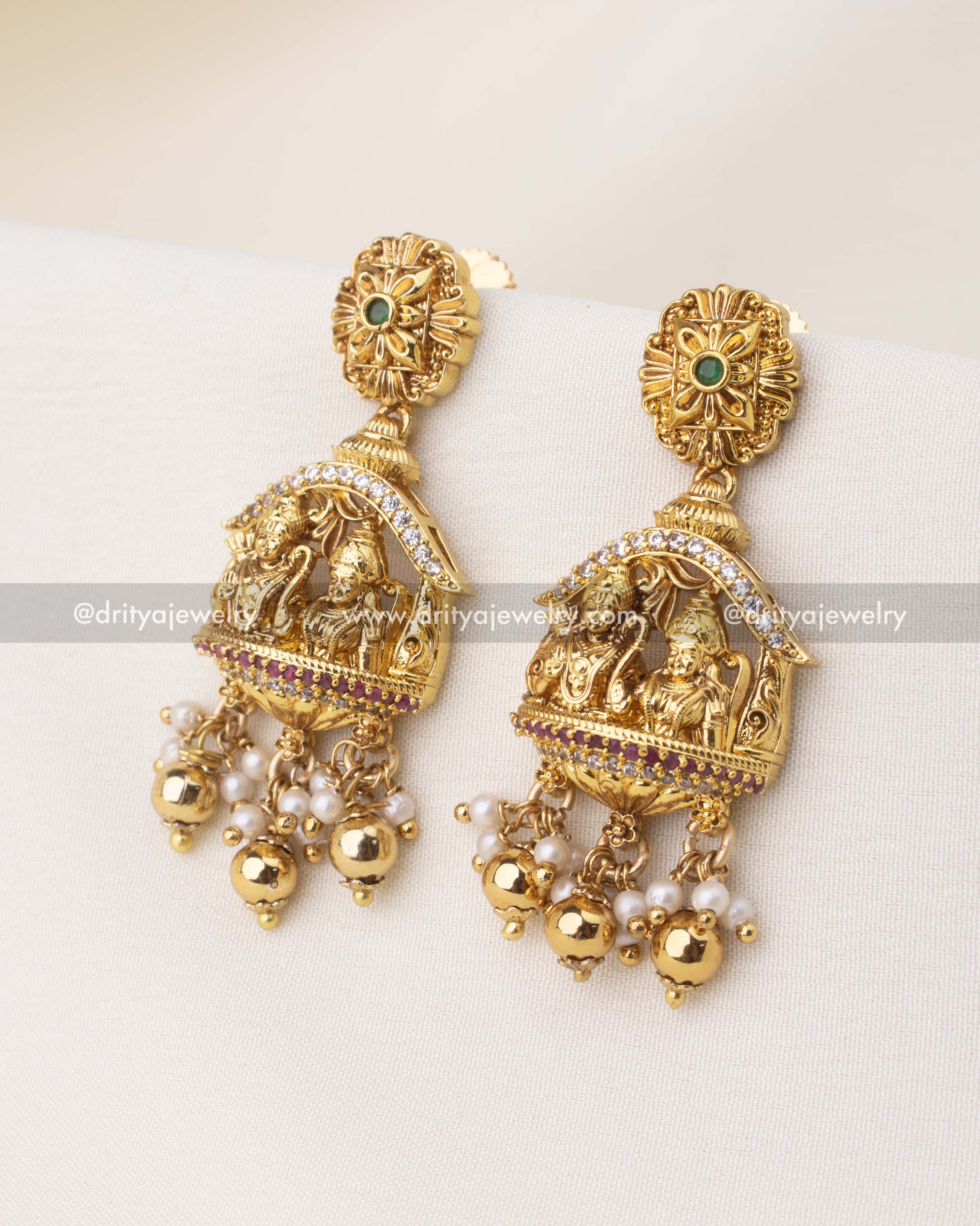 Temple jewelry earrings with Ram Parivar motif, CZ highlights, and pearl-golden bead drops.