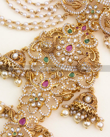 Close-up of top floral and peacock motifs with ruby and emerald kundan stones.