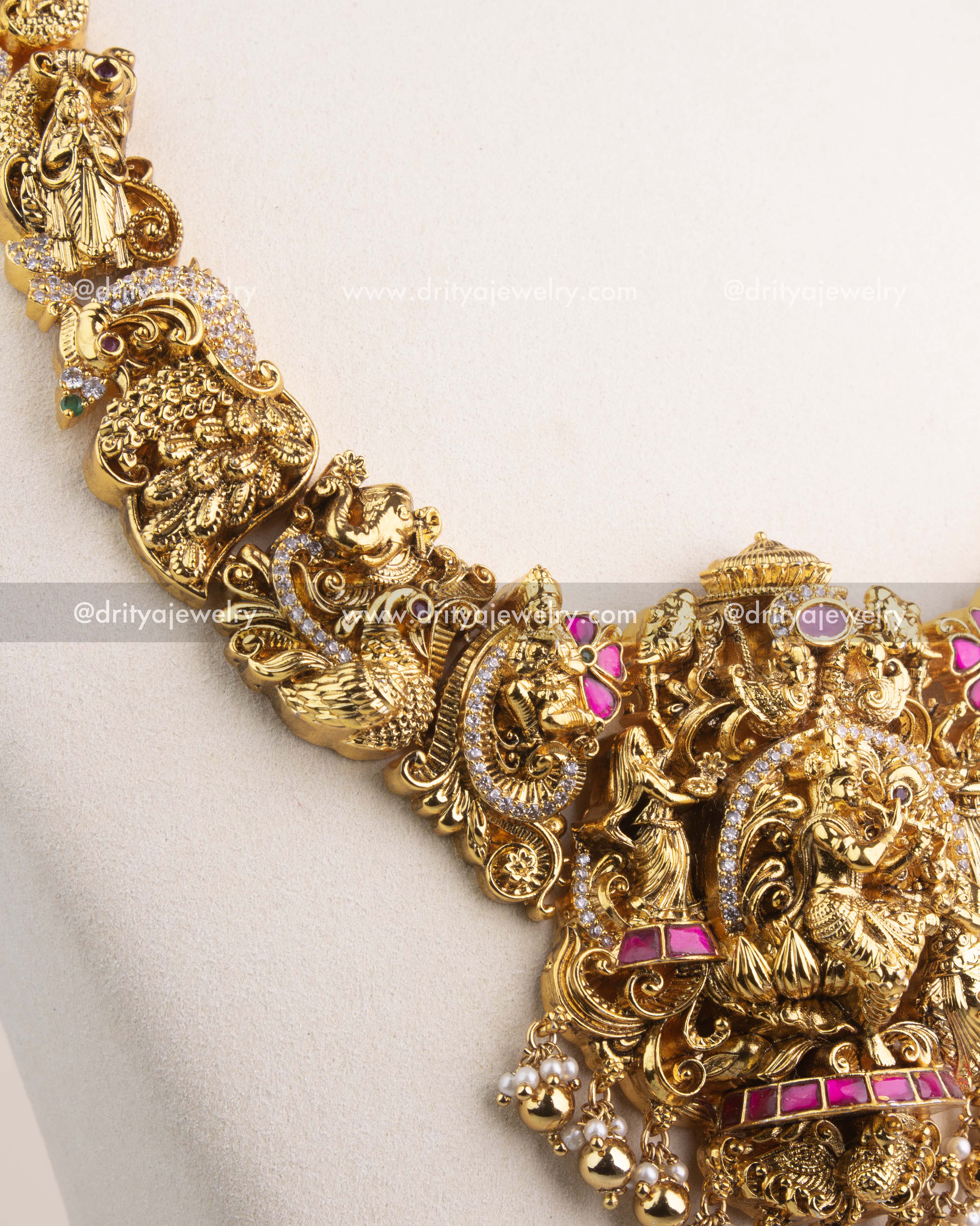 Detailed view of long necklace chain with temple motifs, peacocks, and floral carvings.