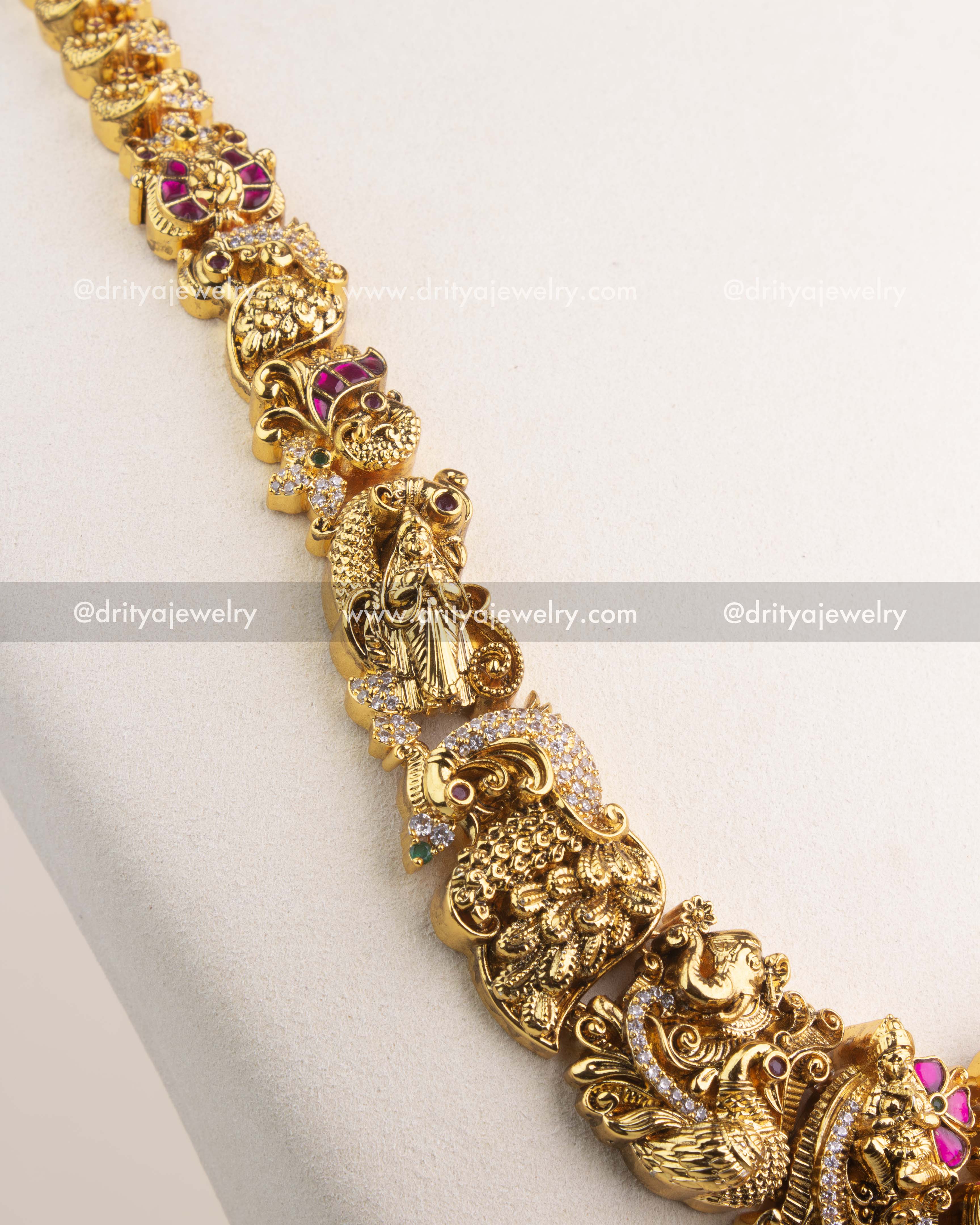 Detailed view of long necklace chain with temple motifs, peacocks, and floral carvings.