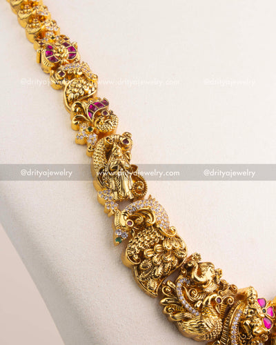 Detailed view of long necklace chain with temple motifs, peacocks, and floral carvings.