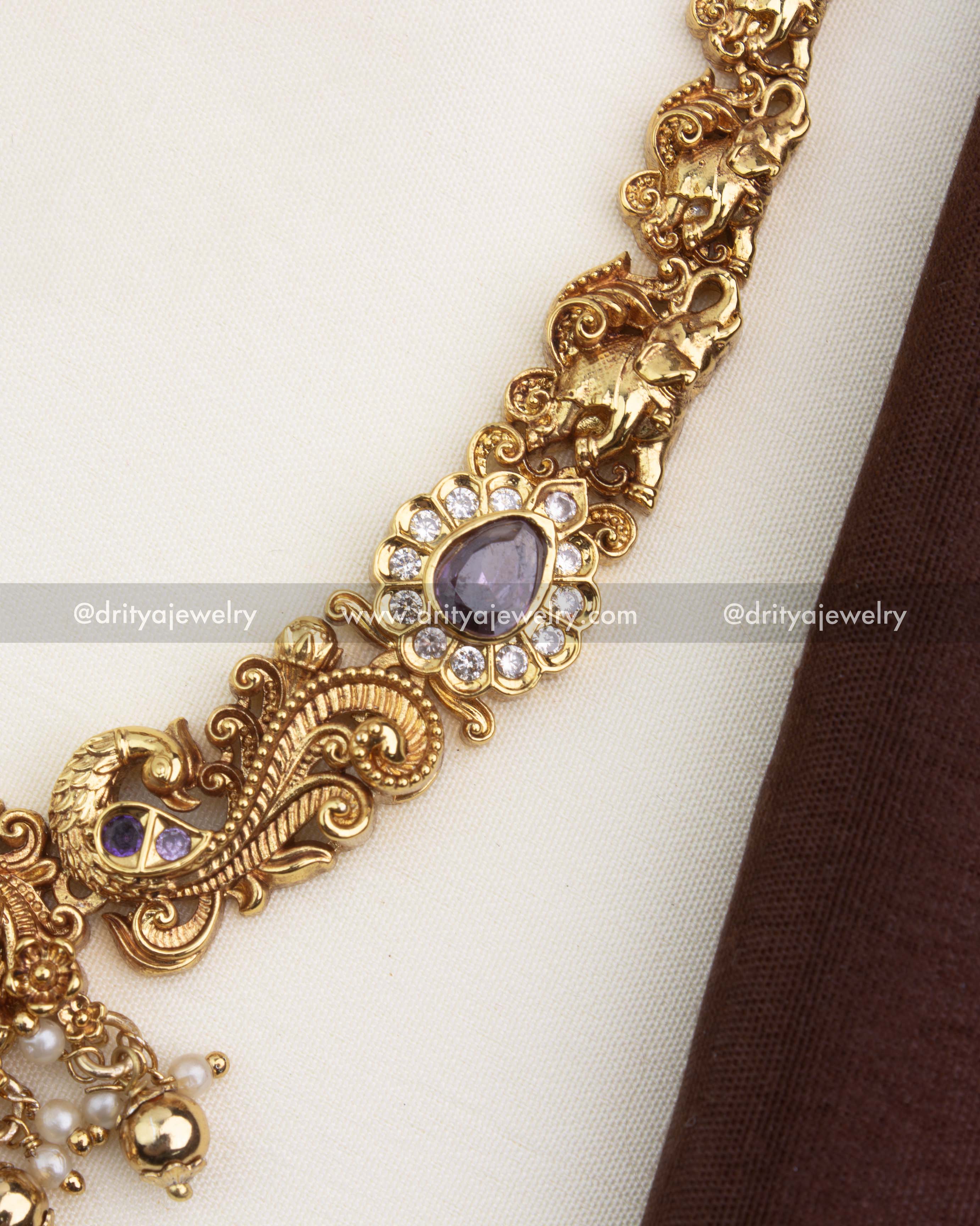 Close-up of temple necklace showing intricate Nakshi carvings, elephant motifs, and lavender stone accents.