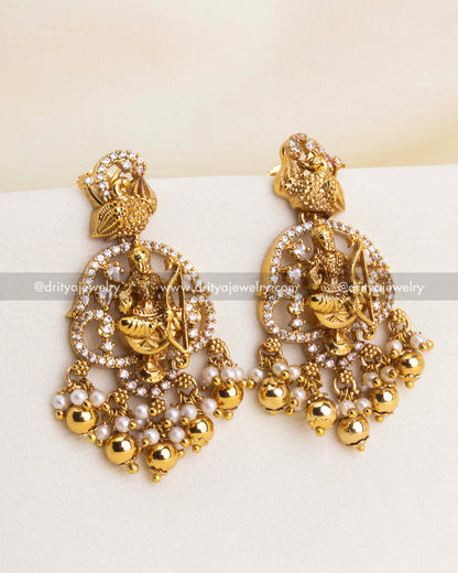 Close-up of matching danglers with deity motifs, peacock detailing, and bead clusters.