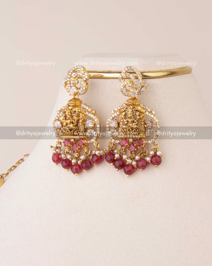 Temple-style earrings featuring Goddess Lakshmi motif with ruby beads and CZ detailing.