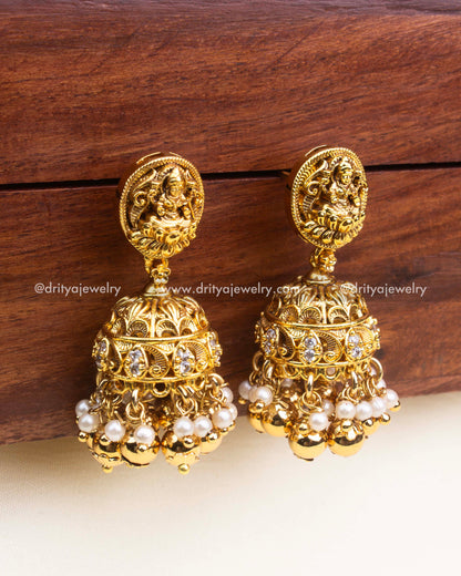 Temple-style gold jhumka earrings with Lakshmi motif, pearl and gold ball drops.