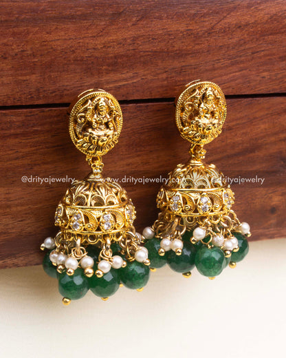 Gold-plated Nakshi jhumka earrings with goddess motif and green bead drops.