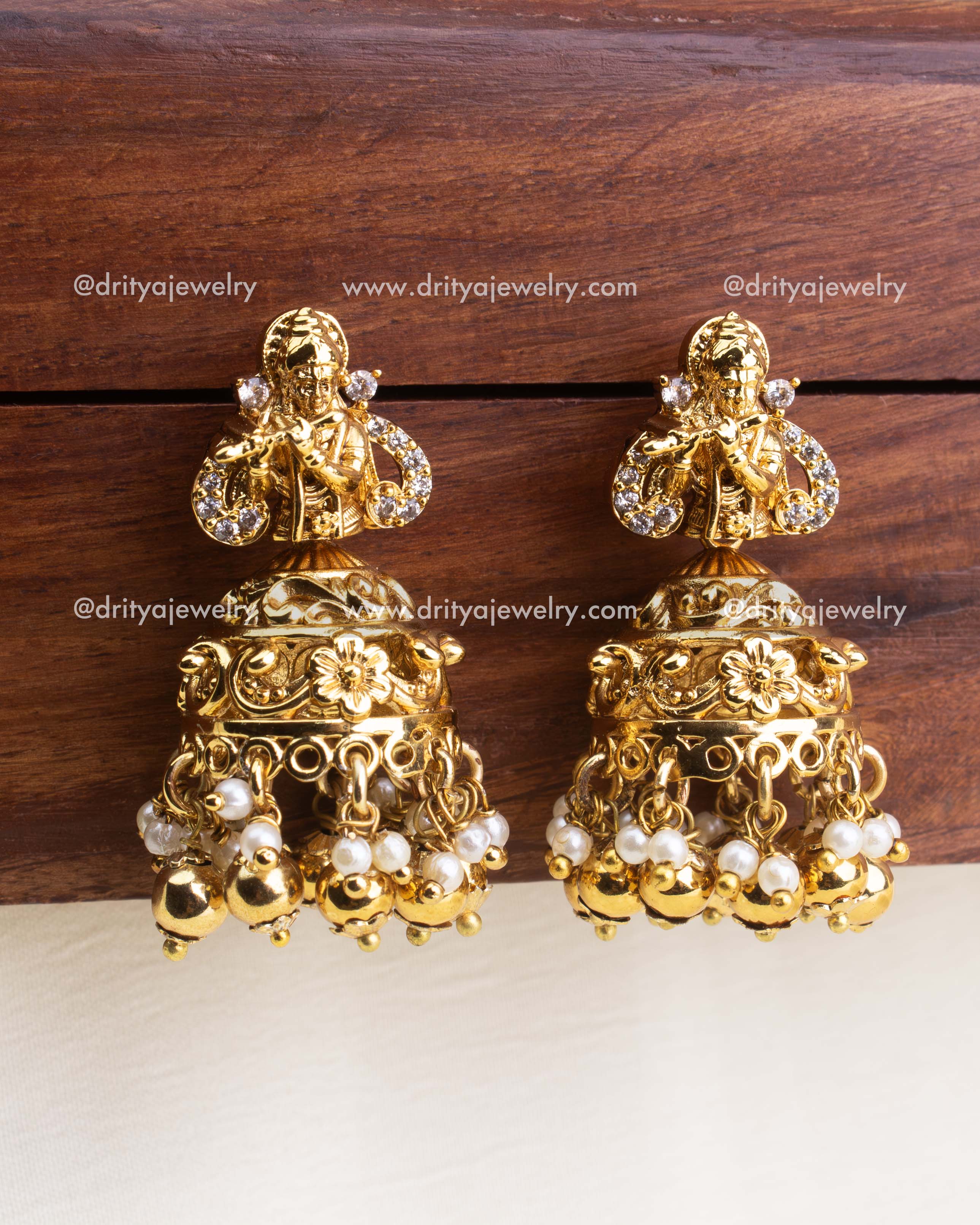 Matching jhumka earrings with Krishna motif and golden bead hangings.