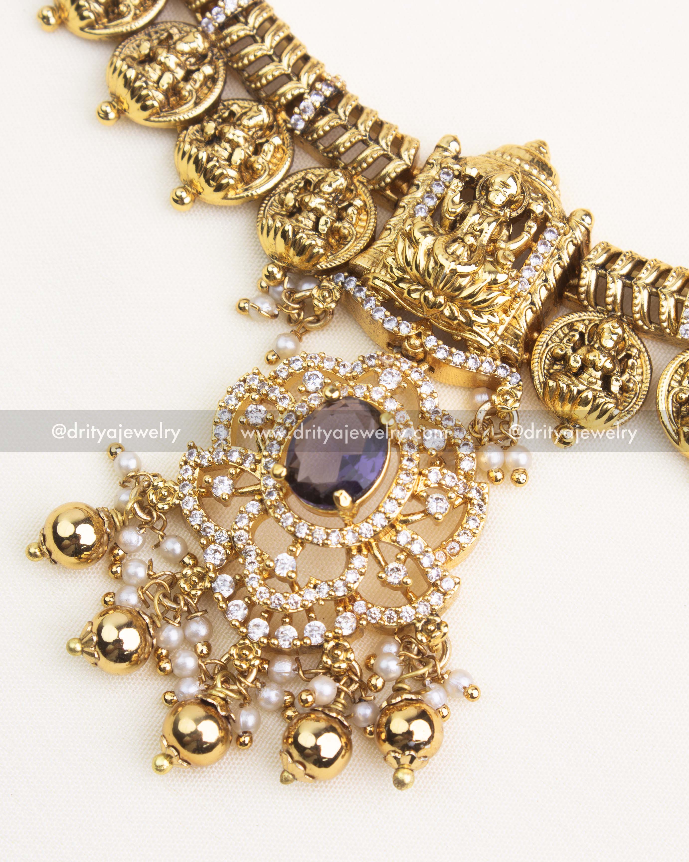 Close-up of temple-style pendant with purple center stone, CZ detailing, and pearl drops.