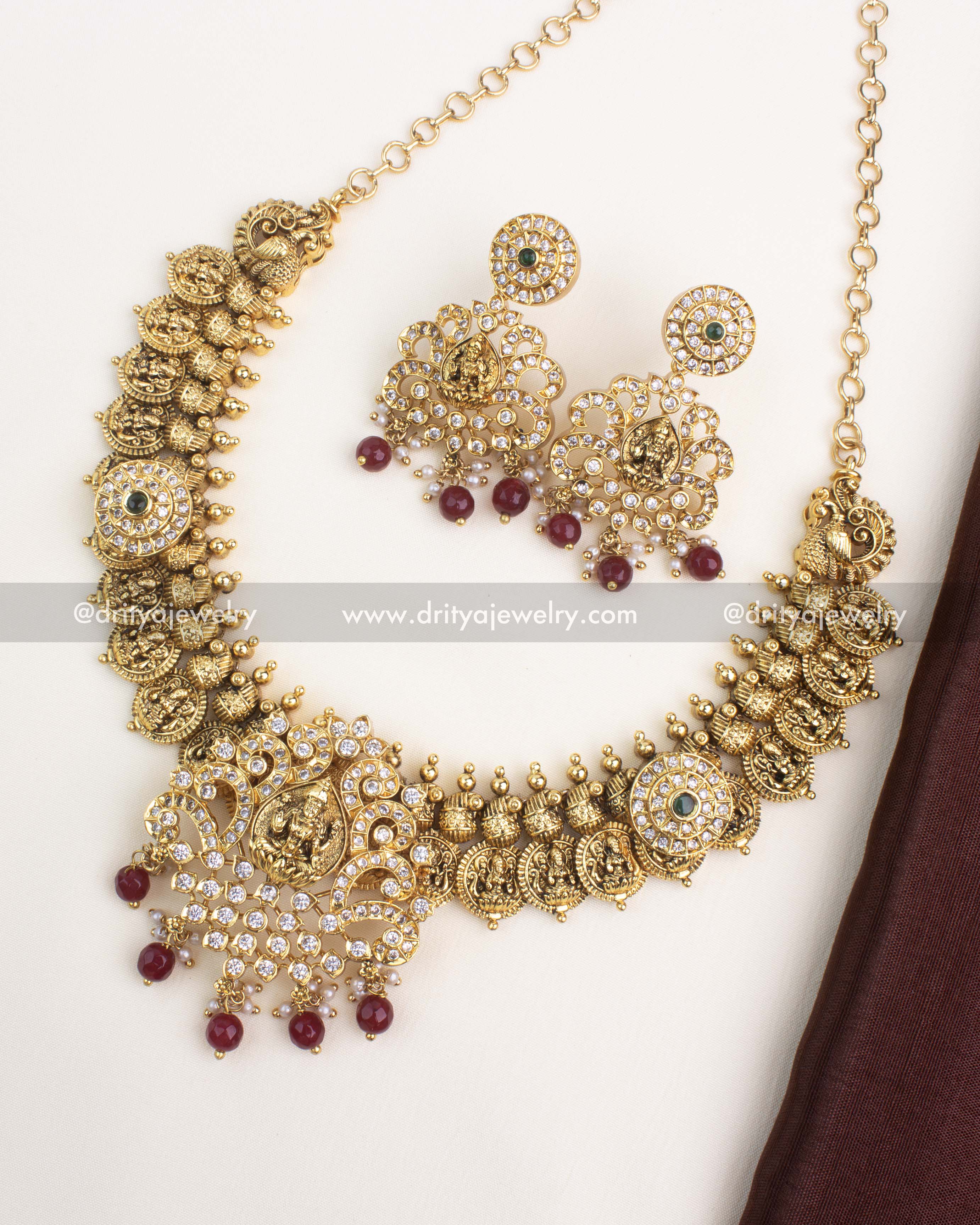 Temple-inspired Nakshi Kasulu necklace with Lakshmi motifs, antique gold plating, and ruby red bead drops.
