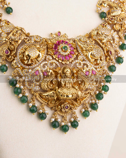 Close-up of long Nakshi necklace featuring Lakshmi motif, ruby kemp stones, and green bead drops.