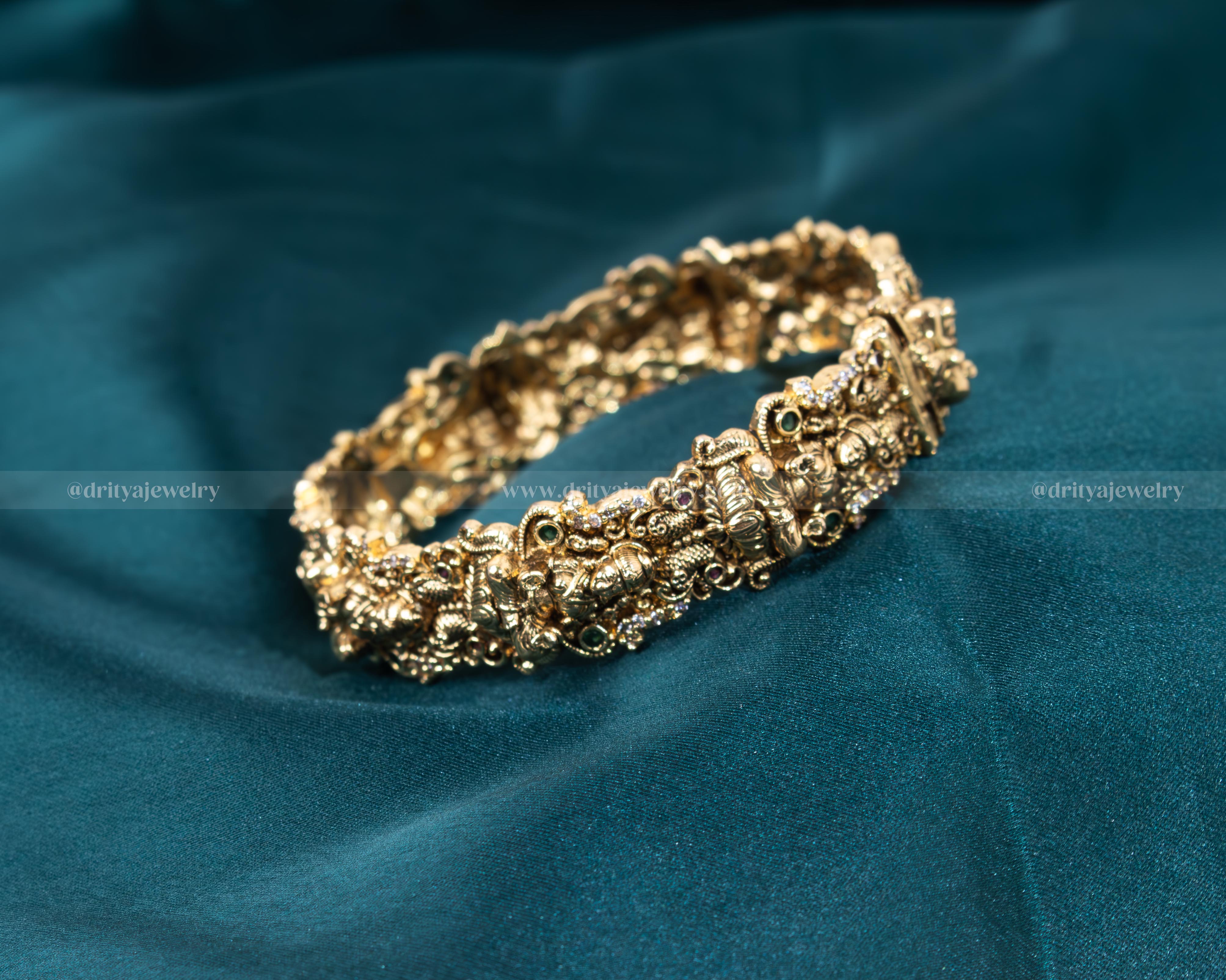 Dritya Jewelry's Nakshi Openable Bangle featuring intricate traditional carvings and adorned with faux rubies and emeralds, perfect for cultural and festive occasions.