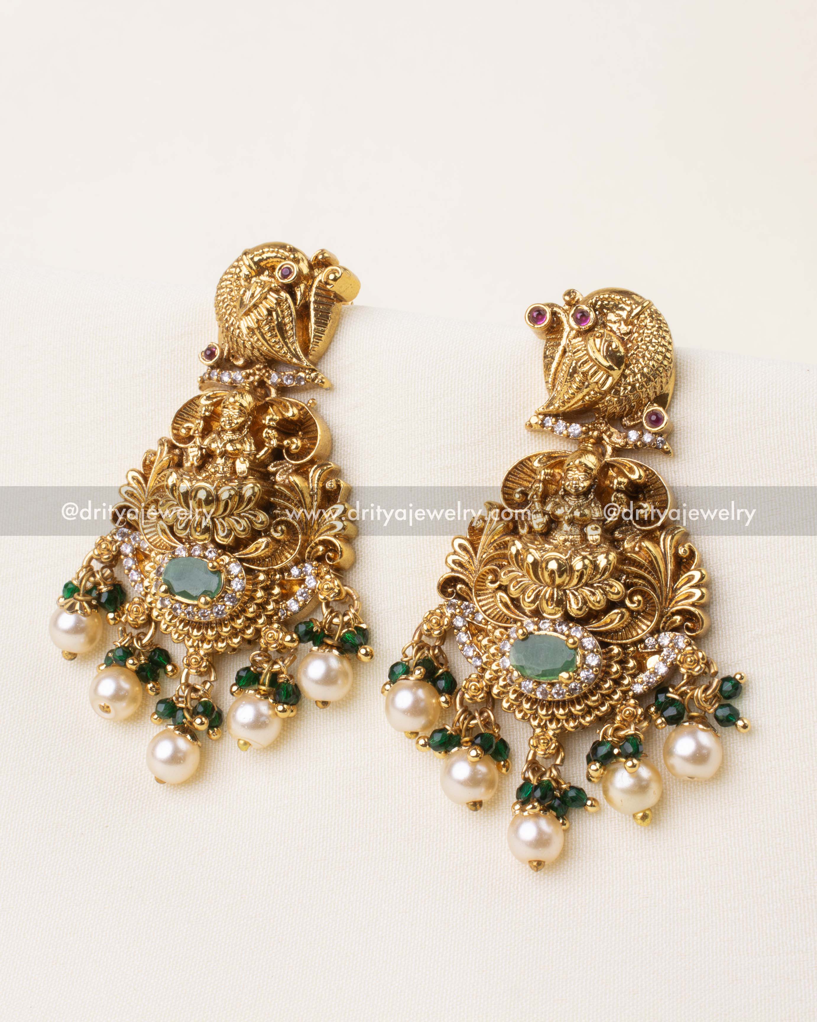 Temple-inspired gold earrings featuring goddess motif and green bead drops.