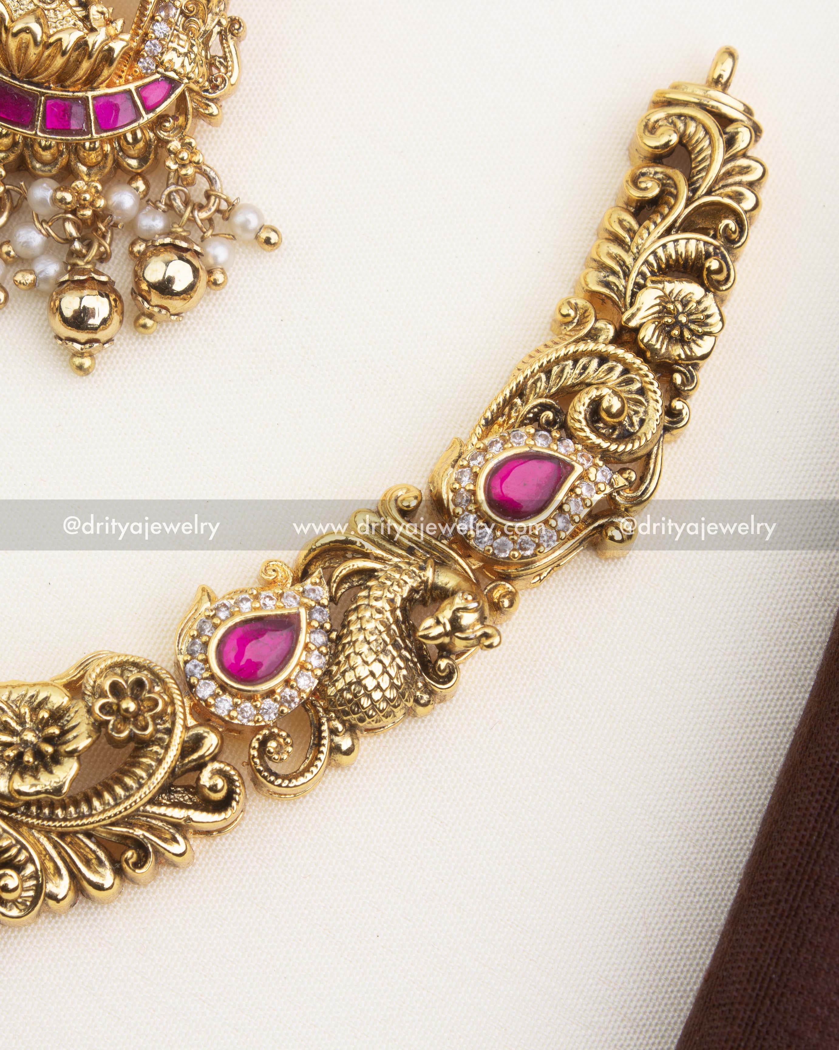 Detailed close-up of Nakshi carving, peacock motifs, ruby kemp inlay, and antique gold finish.