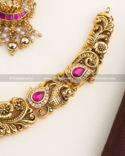 Detailed close-up of Nakshi carving, peacock motifs, ruby kemp inlay, and antique gold finish.