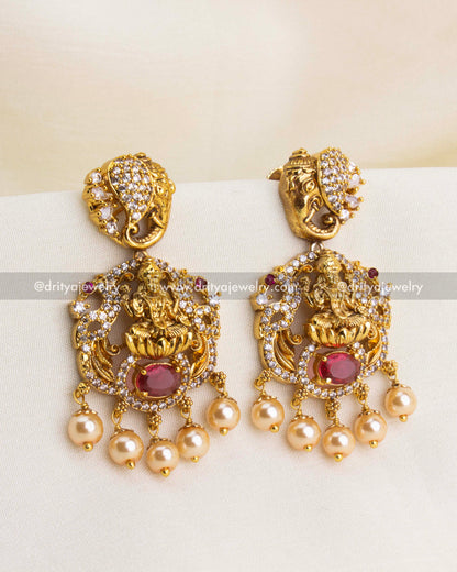 Premium Nakshi temple danglers with Goddess Lakshmi, red oval stone, CZ accents, and pearl drops.