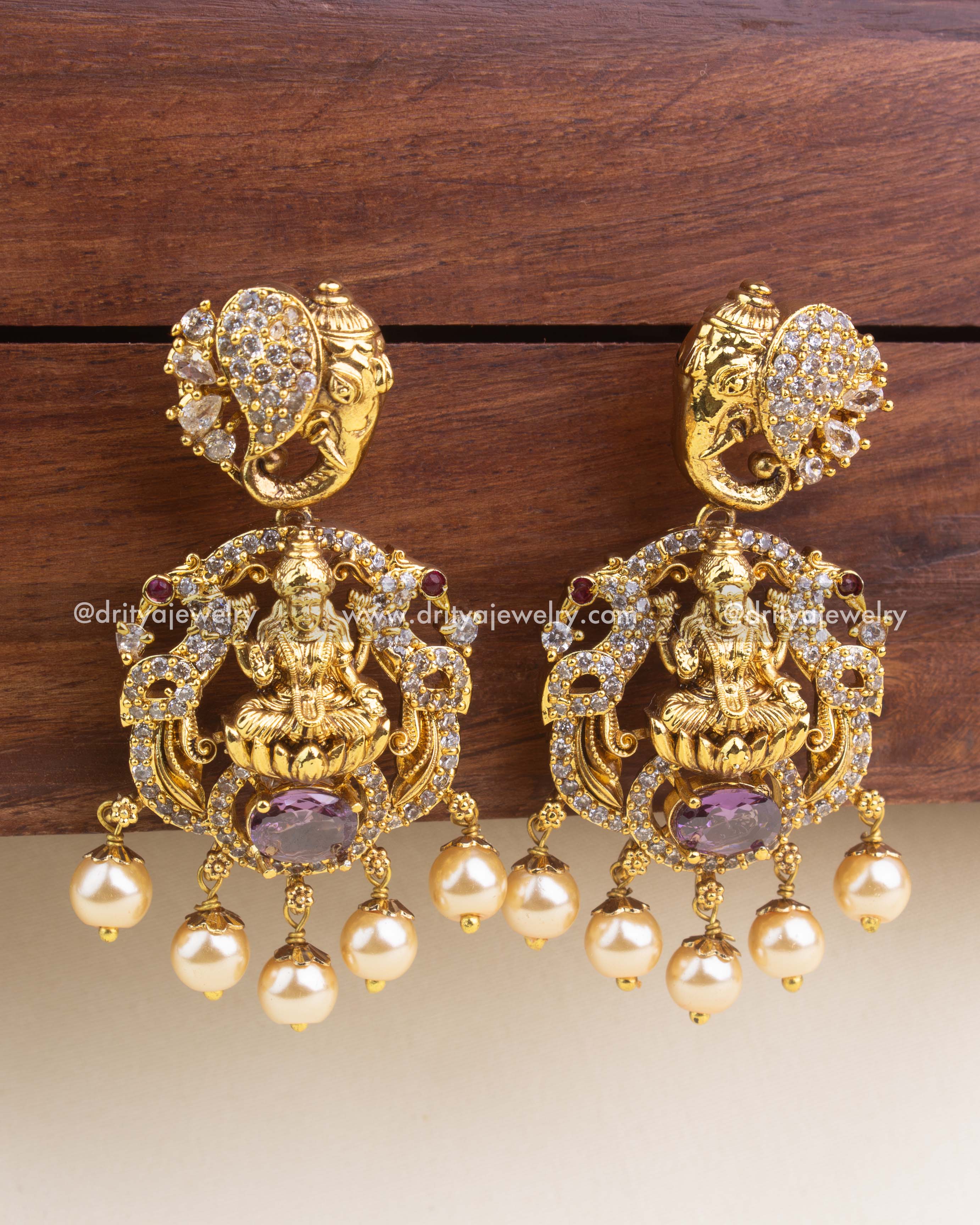 Antique gold temple earrings with purple center stones, intricate nakshi work, and pearl detailing.