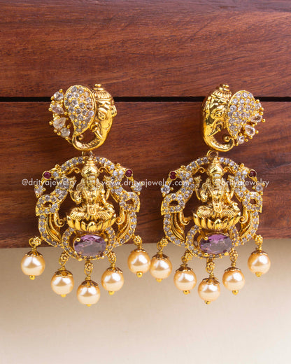 Antique gold temple earrings with purple center stones, intricate nakshi work, and pearl detailing.
