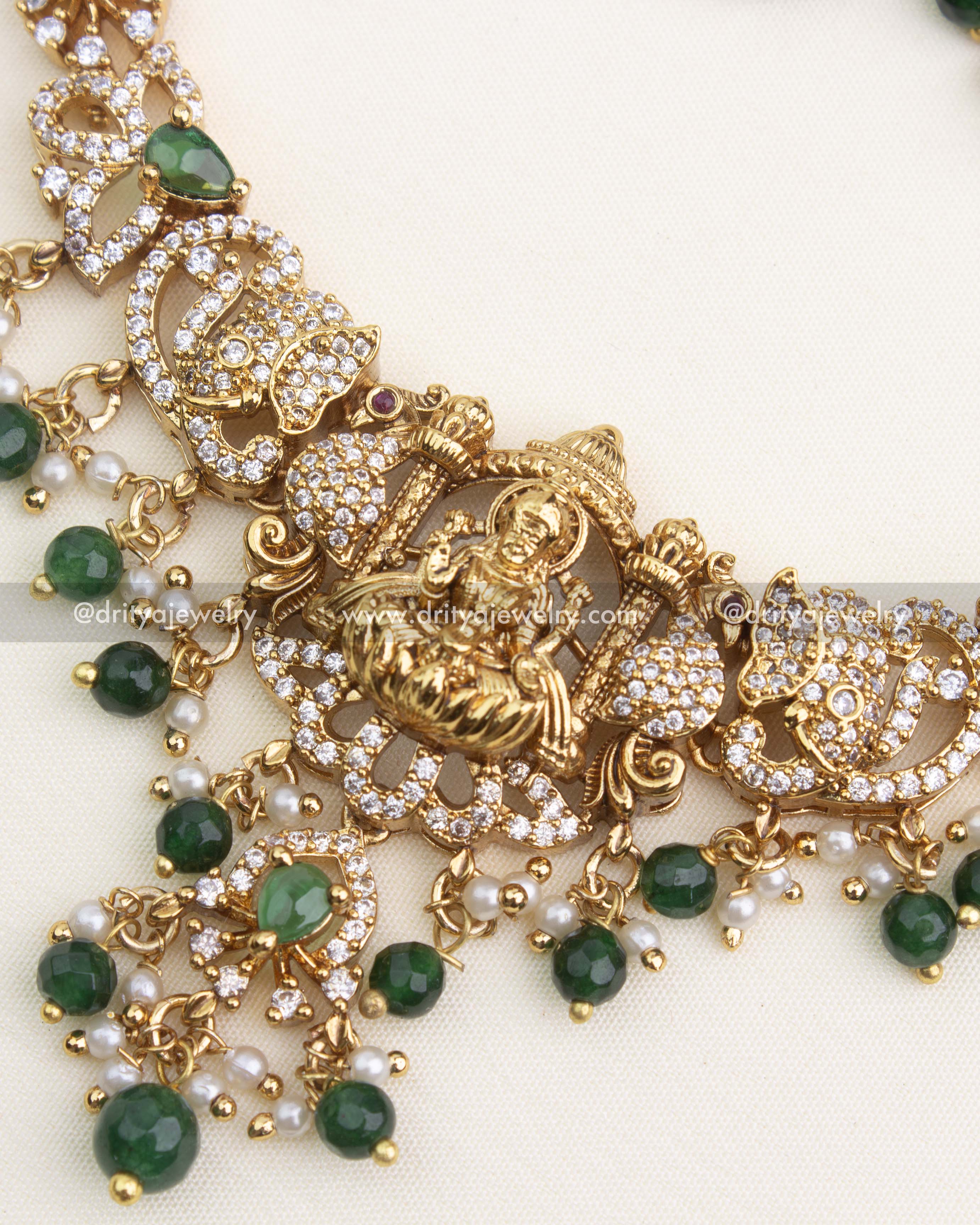 Detailed close-up of Lakshmi pendant with antique nakshi work, CZ stones, and green bead drops.