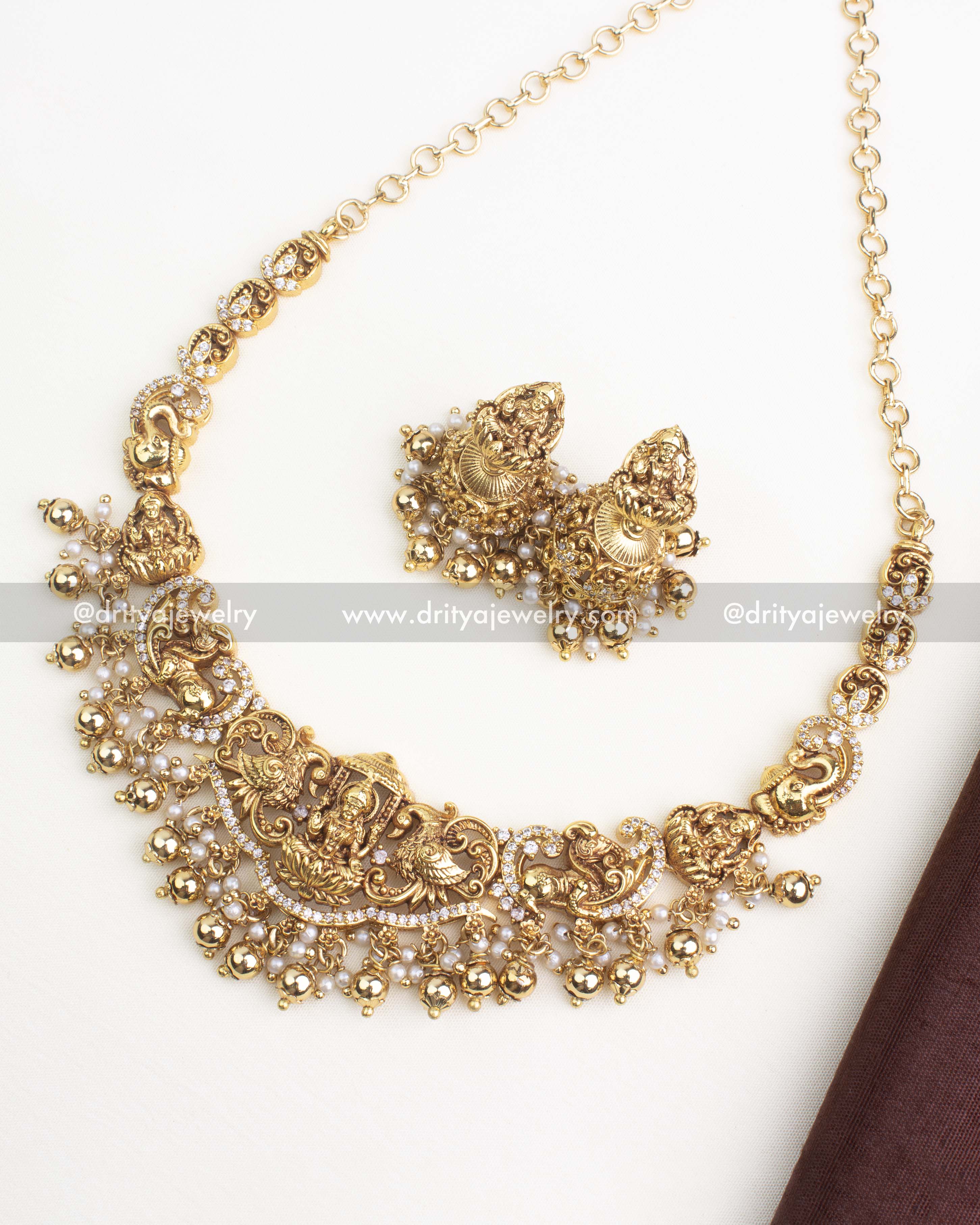 Antique gold temple necklace with Lakshmi pendant, peacock motifs, and matching jhumka earrings with pearl drops