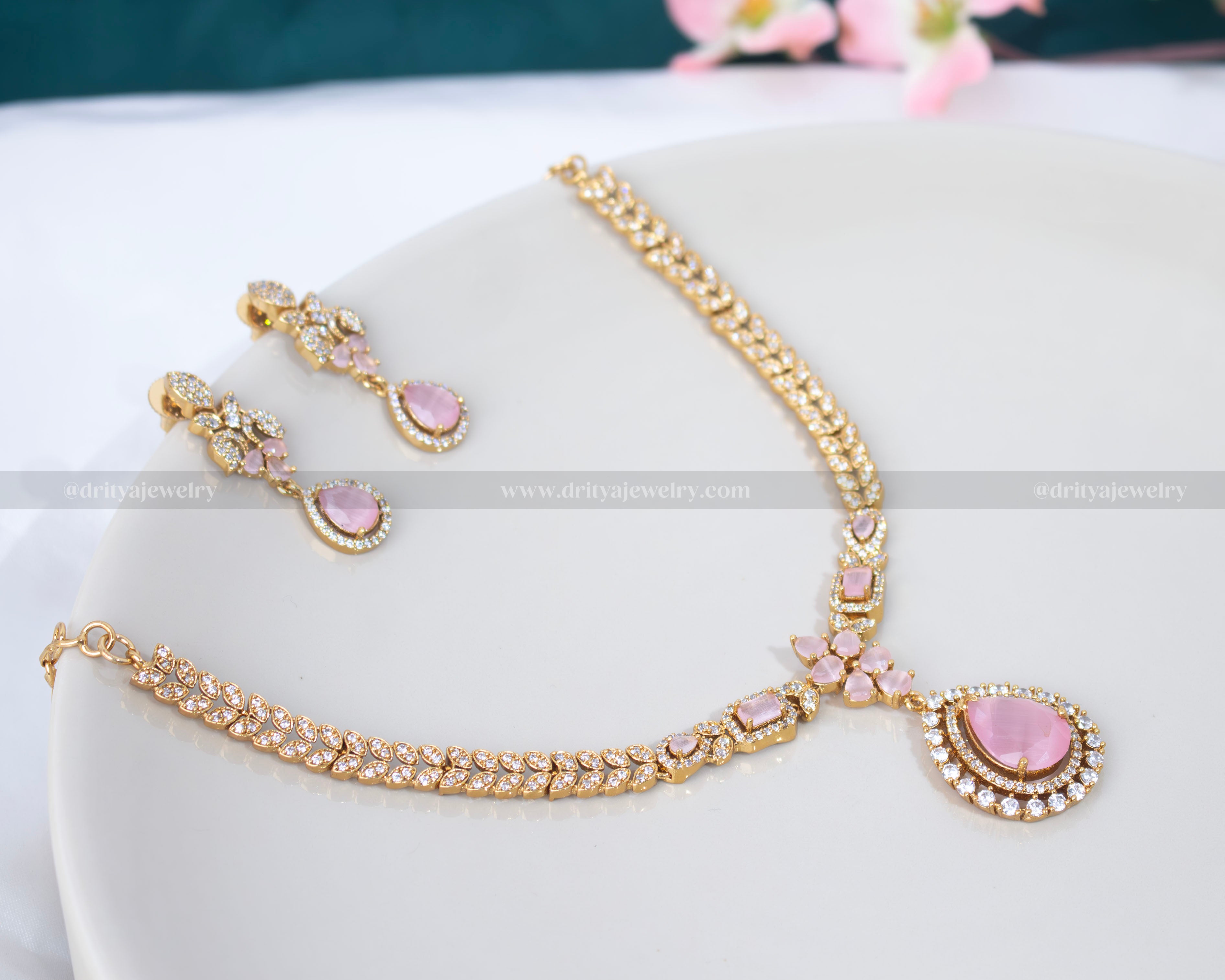 Dritya Jewelry’s gold-plated necklace set featuring a teardrop pendant with pink stones and Cubic Zirconia accents, perfect for formal and festive occasions.