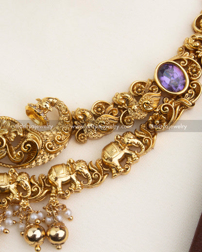 Intricate nakshi carving with elephant motifs and purple stone on the necklace side frame.
