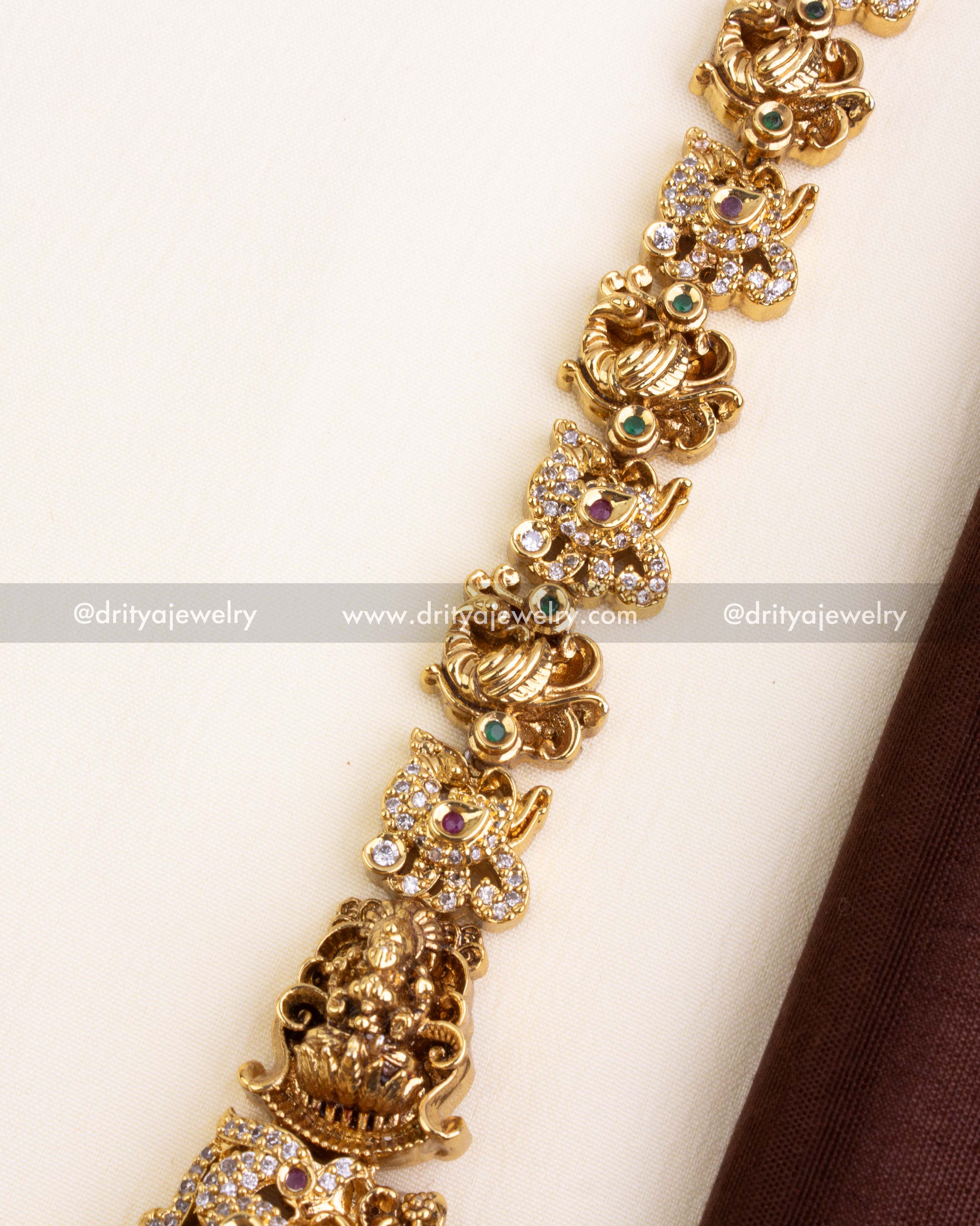 Intricate peacock and goddess motifs with CZ stones and green accents on temple long necklace chain.