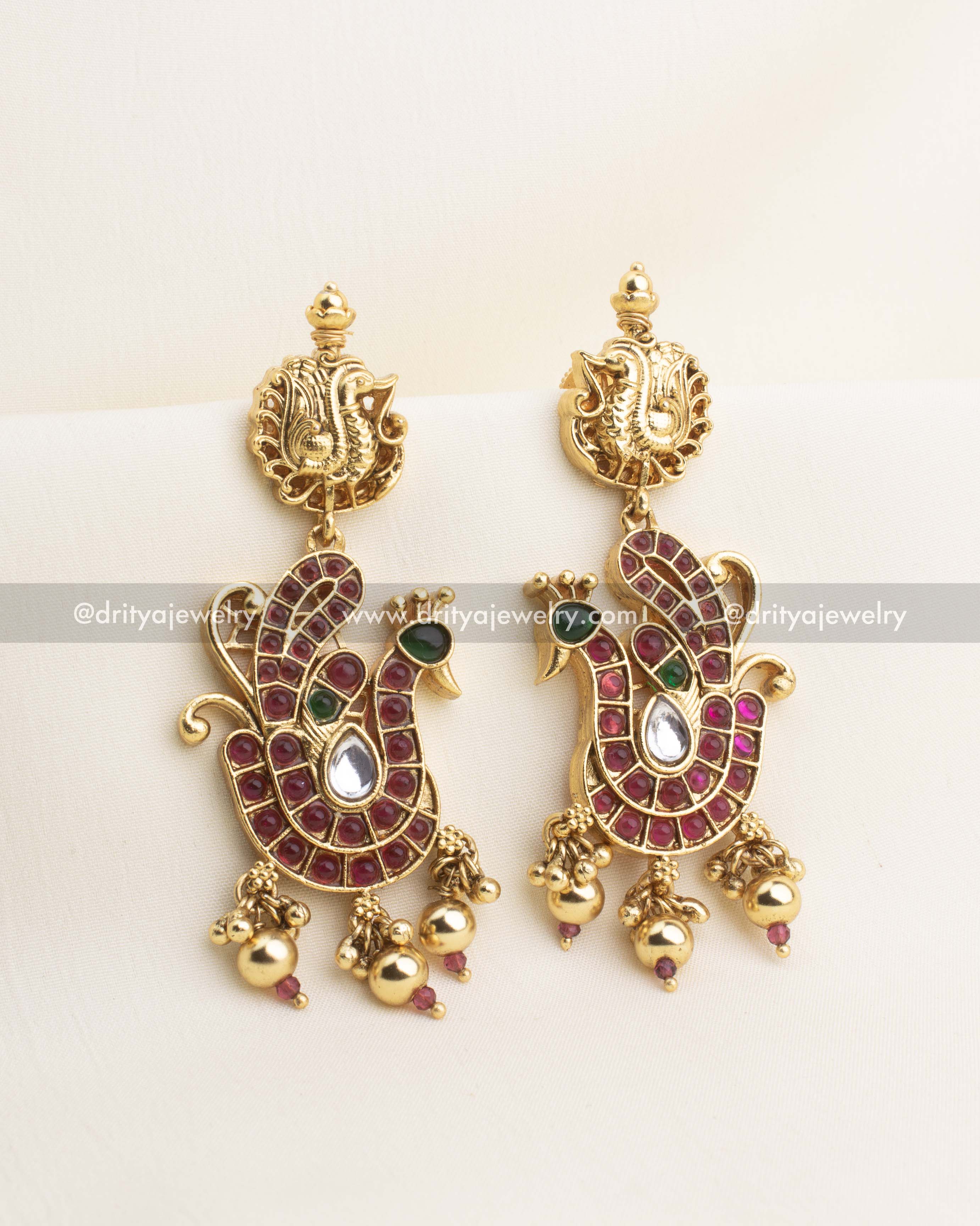 Peacock earrings with ruby stones, green CZ eyes, white CZ drops, and gold ghungroo hangings.