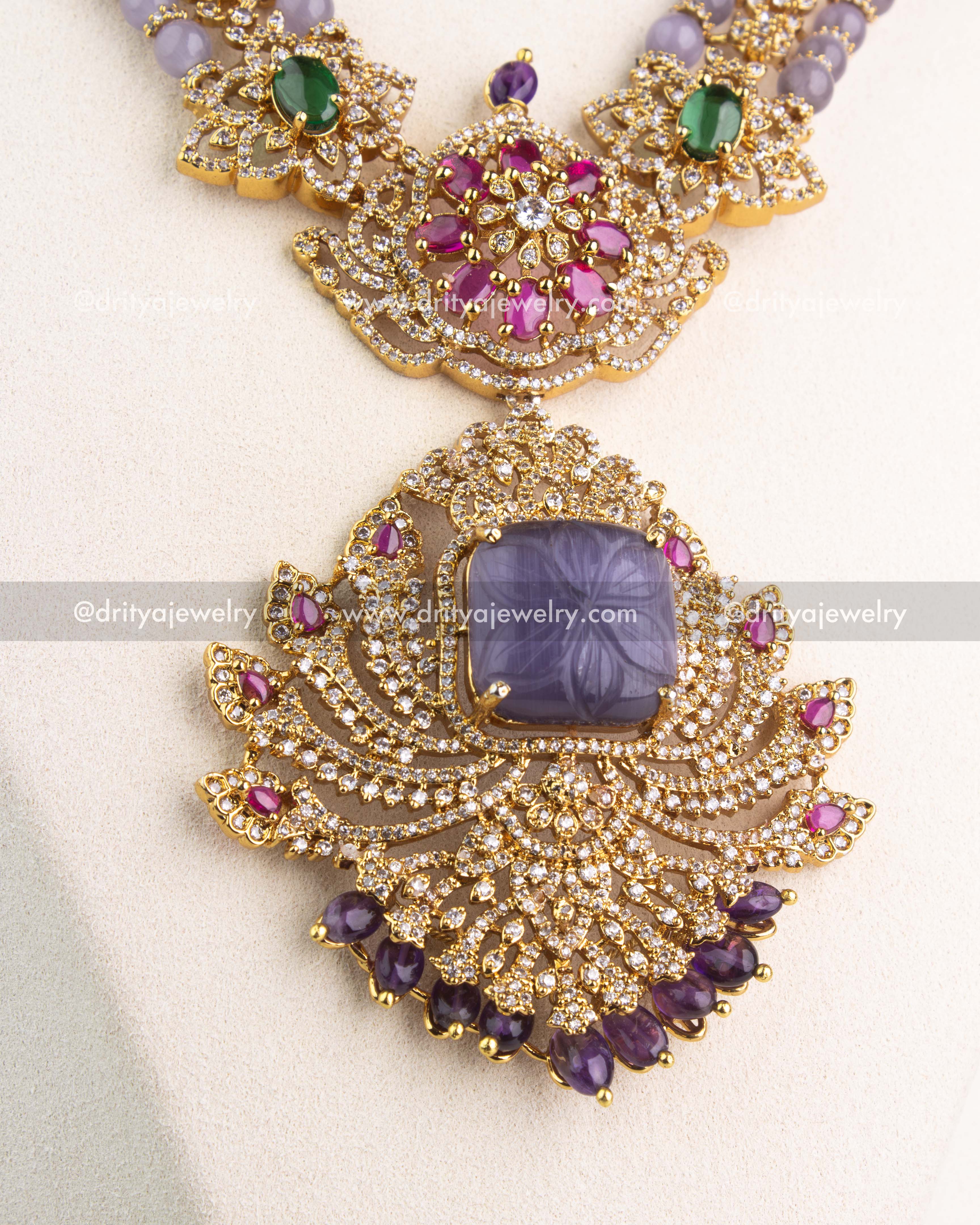 Detailed view of carved lavender centerpiece with CZ stones and ruby pink accents in gold setting.