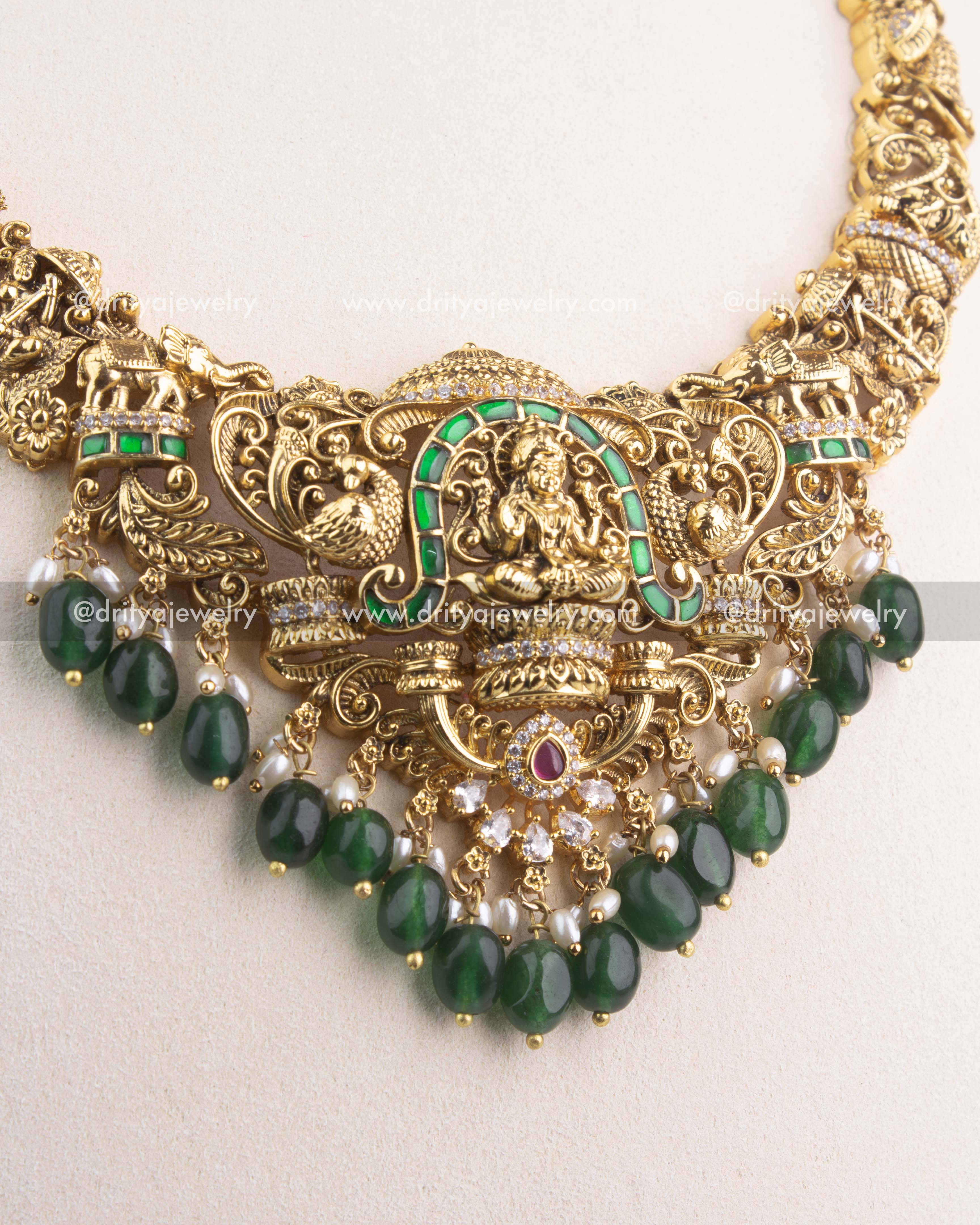 Detailed view of gold Lakshmi Devi pendant with green Jadau stones and pearl bead hangings.