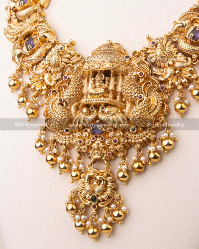 Magnified view of temple pendant with Goddess Lakshmi seated in an ornate shrine.