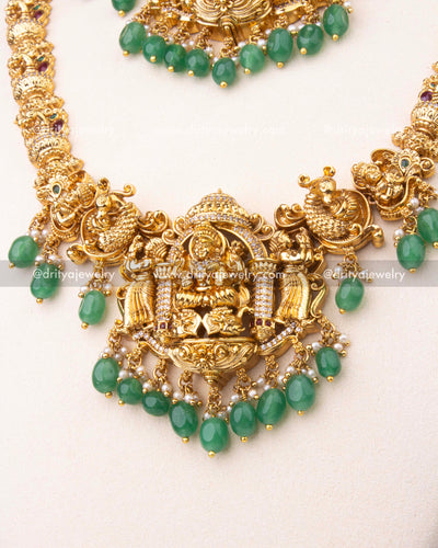 Intricately crafted Lakshmi Devi pendant with green bead drops and antique gold polish.