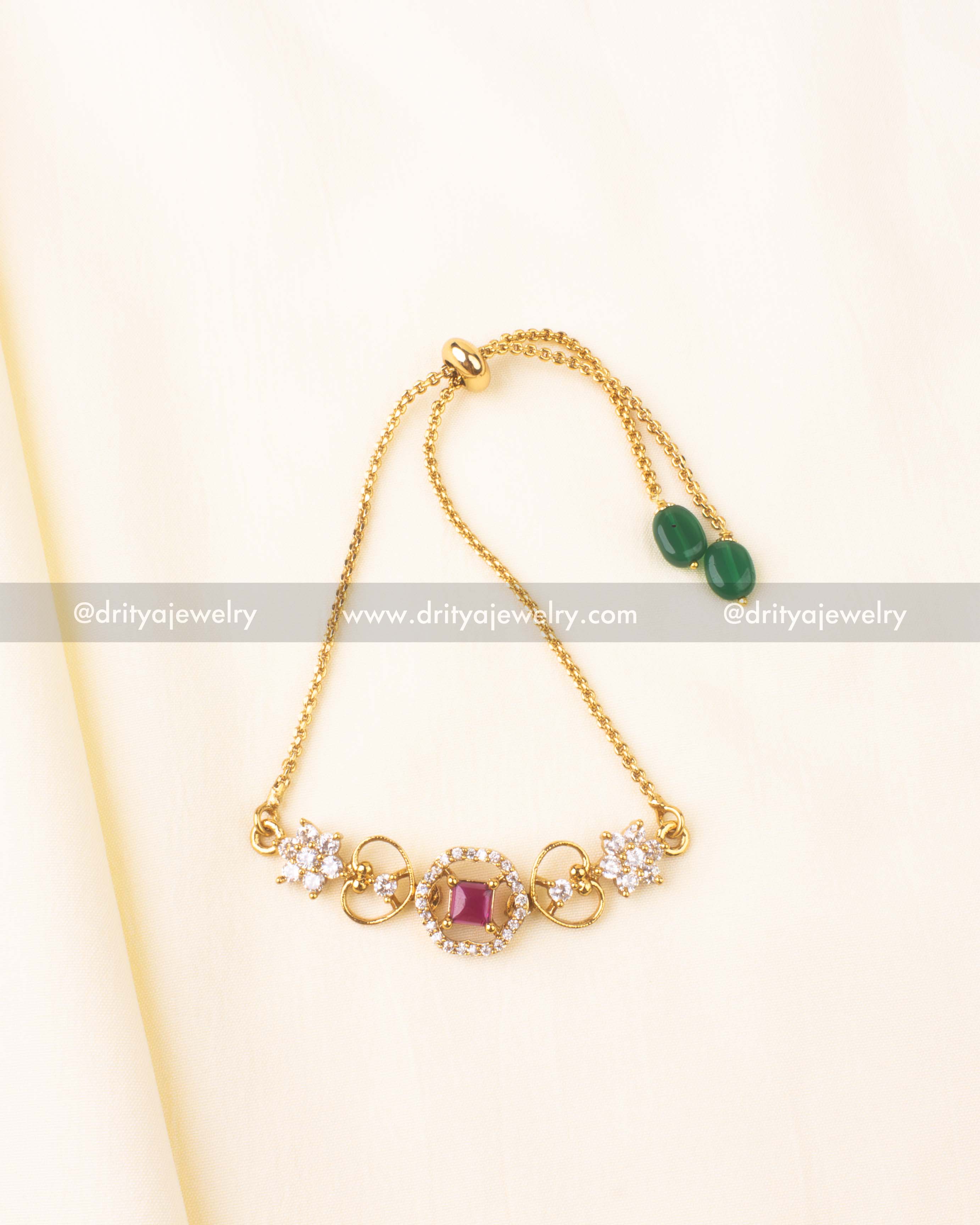 Gold-plated bracelet with pink center stone and CZ heart and flower details.