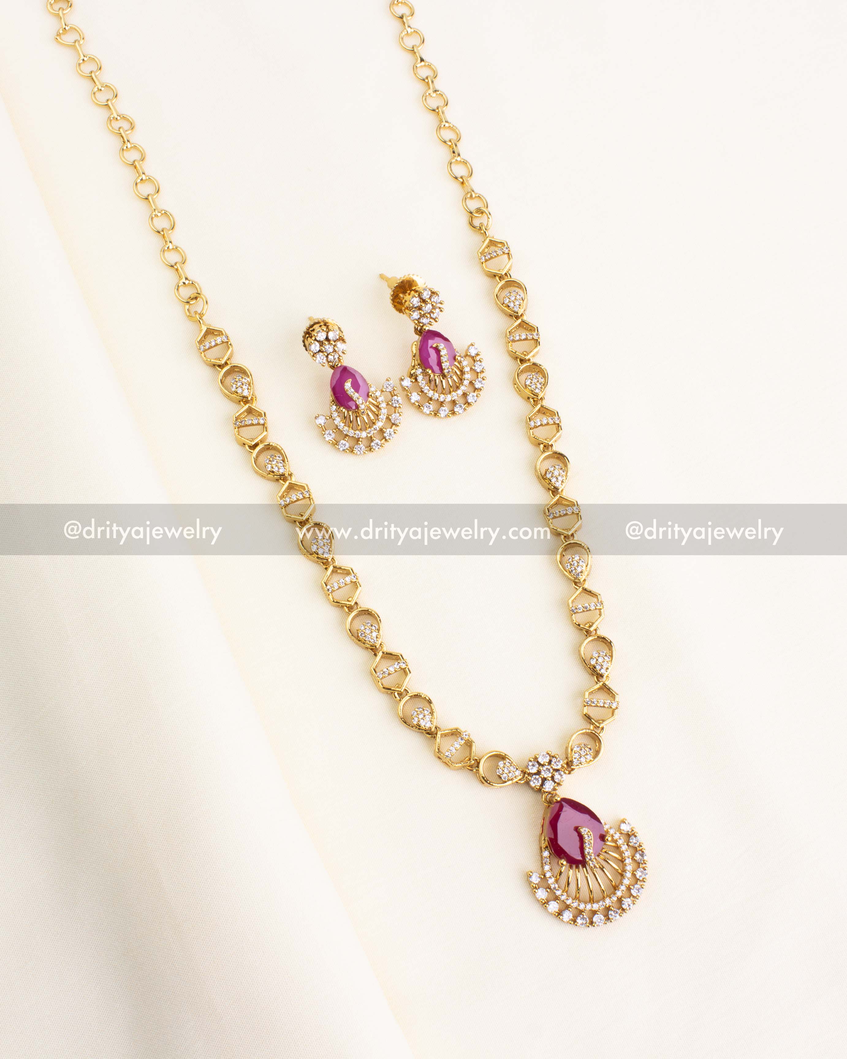 Pink CZ peacock necklace set with earrings on a fabric backdrop