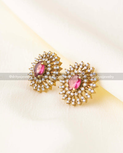 Gold-plated floral stud earrings with pink gemstone center and double CZ halo.