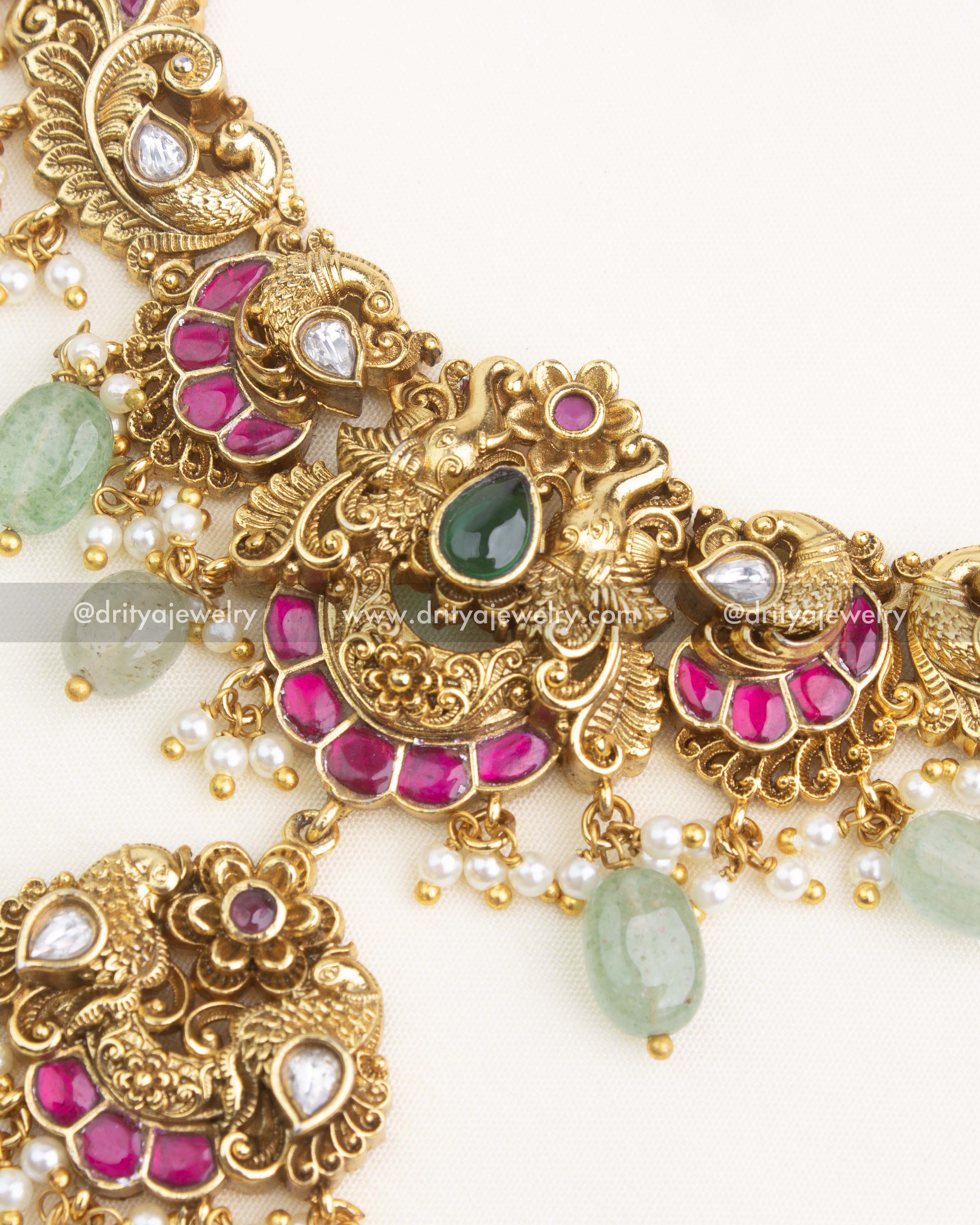 Detailed close-up of necklace centerpiece with peacock designs, pink kemp inlay, polki kundan stones, and gemstone drops