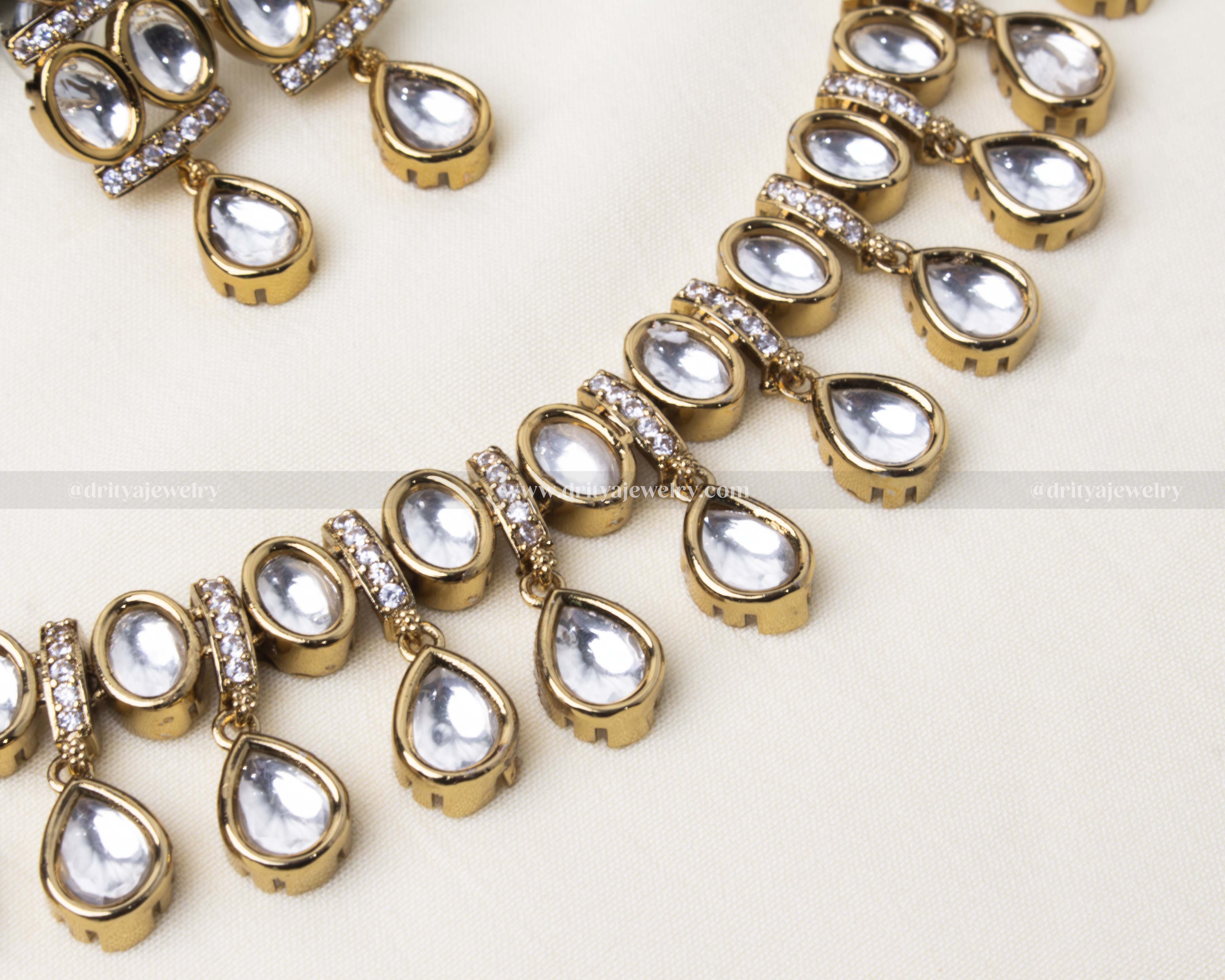 Traditional polki kundan short necklace with teardrop-shaped stones and gold-toned finish, paired with matching earrings.