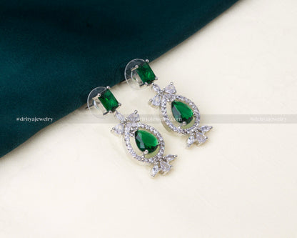 Elegant American diamond necklace set featuring green stones, matching earrings, and a maang tikka with a silver-toned finish.