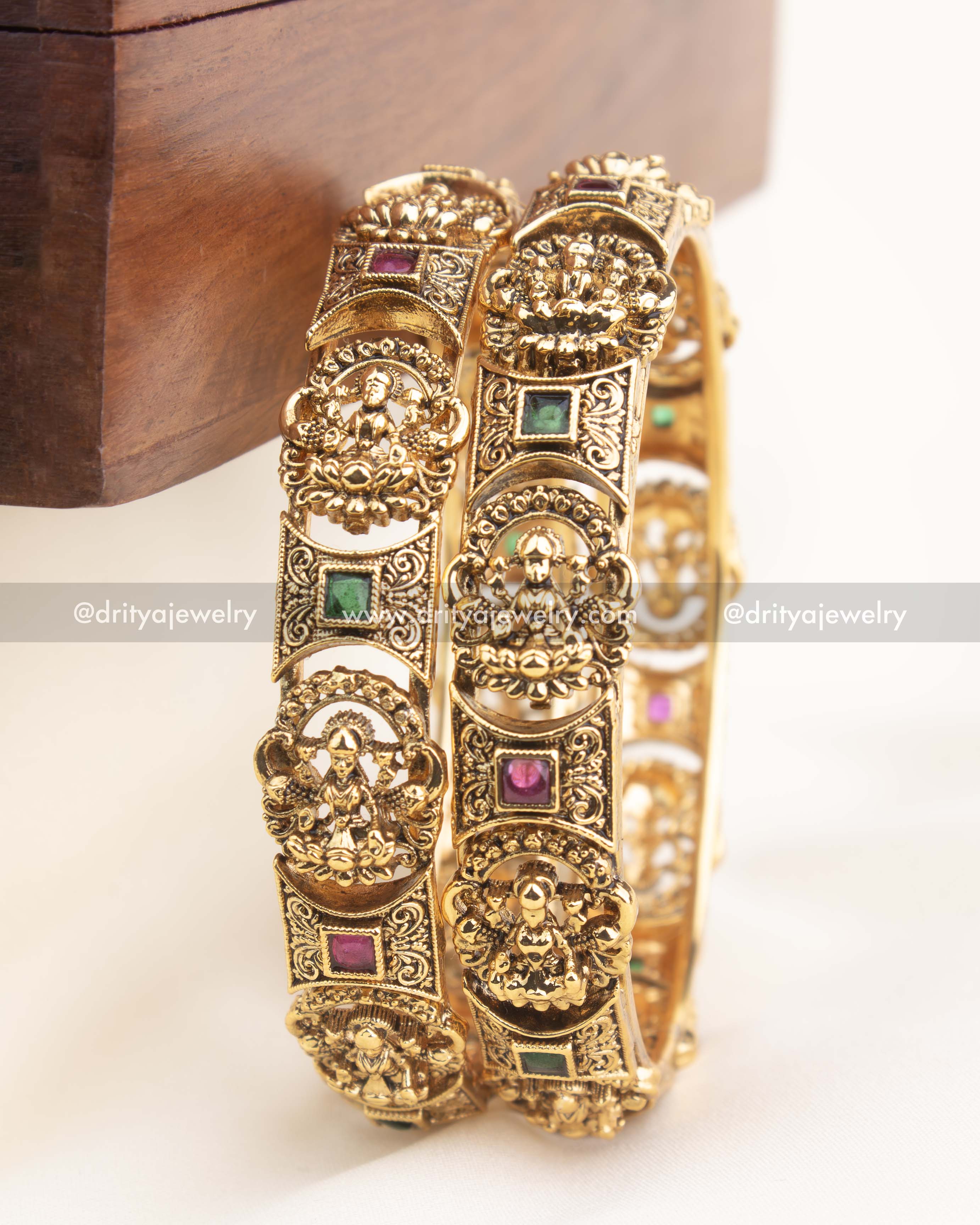 Antique gold temple bangles with intricate goddess engravings and ruby–emerald accents by Dritya Jewelry.