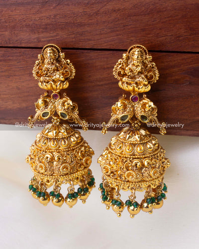 Large antique gold temple Jhumkas with Goddess Lakshmi motif and emerald bead accents.