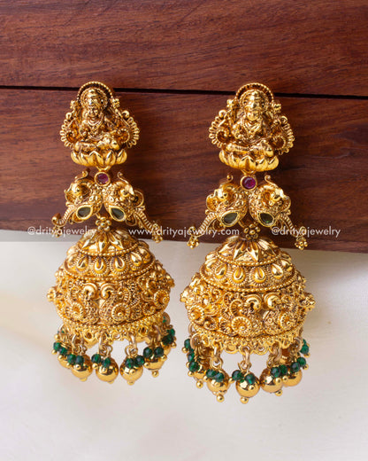 Large antique gold temple Jhumkas with Goddess Lakshmi motif and emerald bead accents.